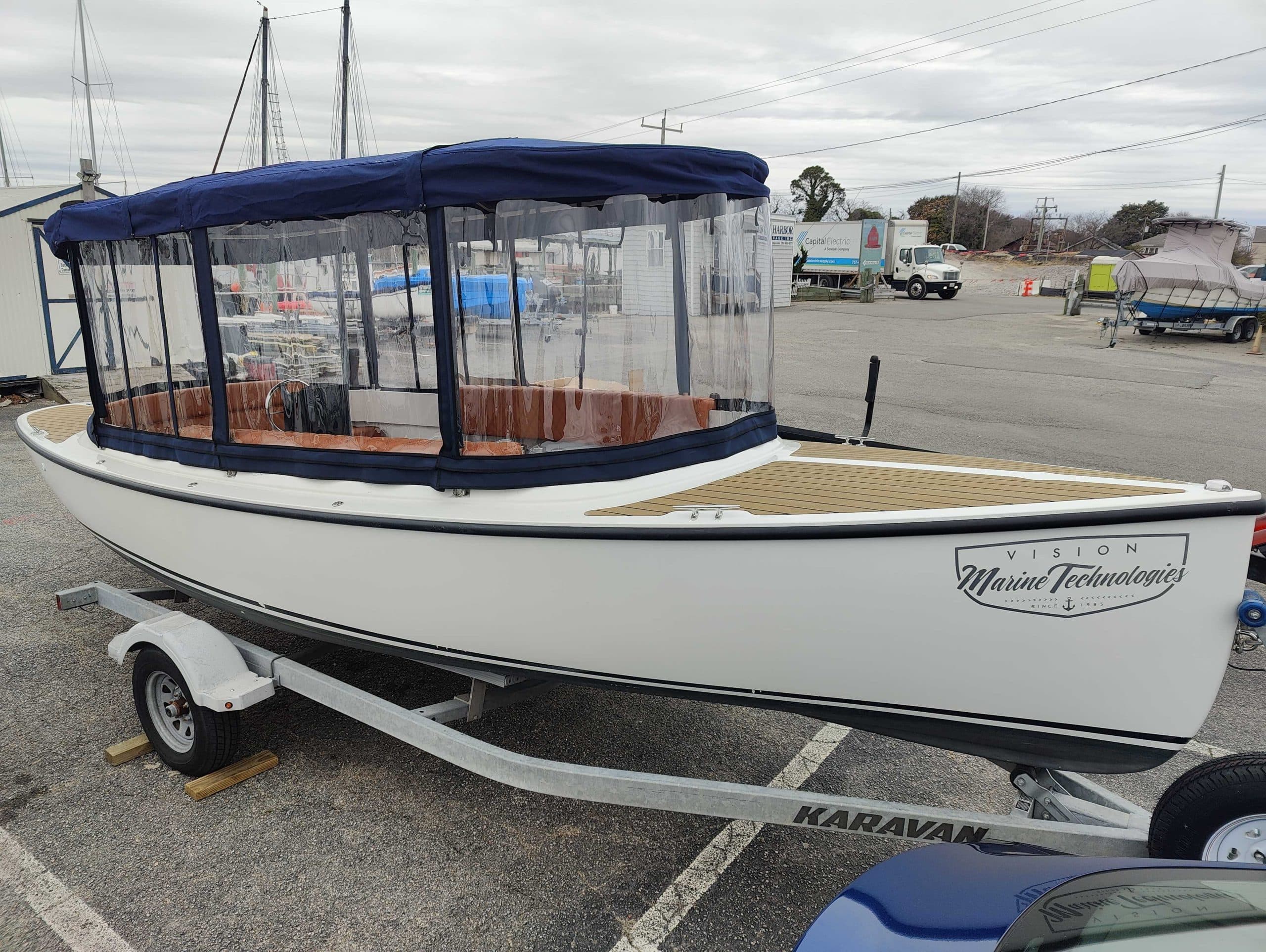 2024 Vision Marine Fantail boat on a trailer, featuring a navy canopy, enclosed side curtains, and wood-look deck.