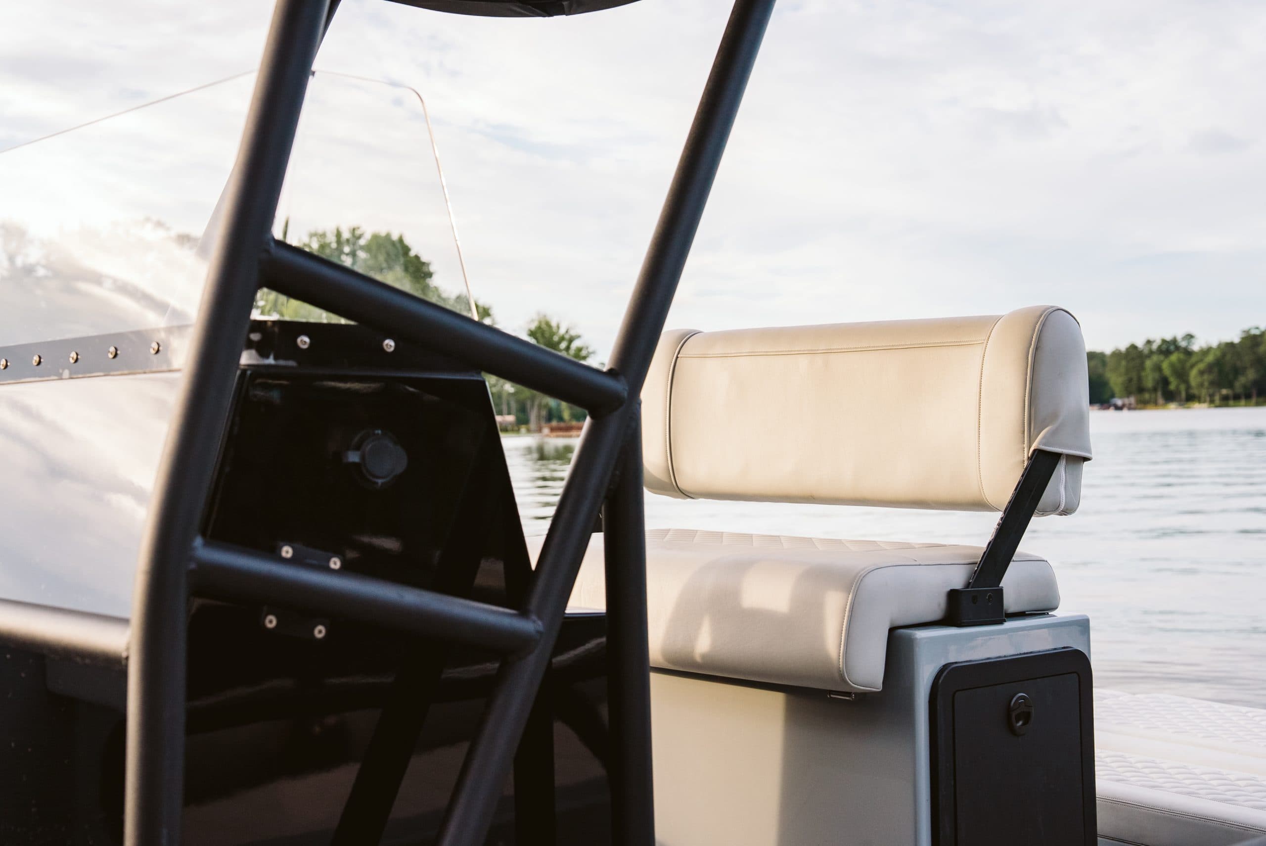 Close-up of Halevai model2050 boat helm and cushioned passenger seating on calm water.
