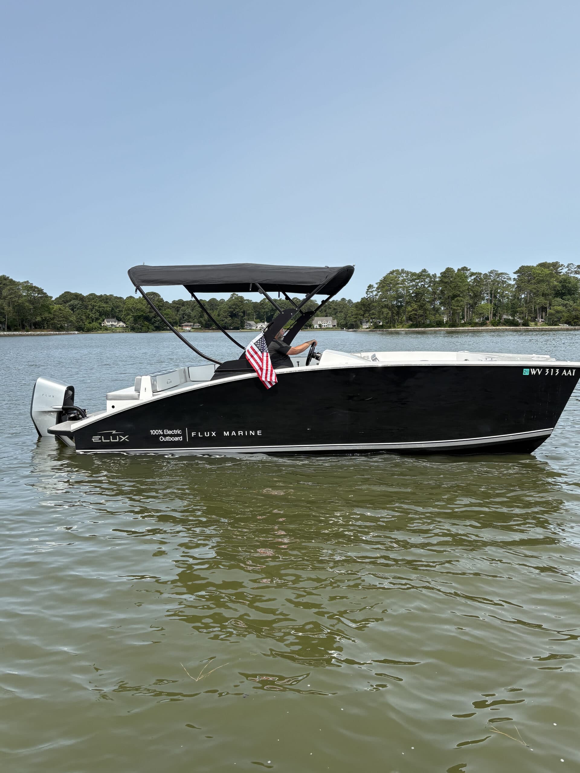 Flux Marine GFX Stealth viewed broadside from the water, showing the hull, center console, canopy, and stern outboard motor.