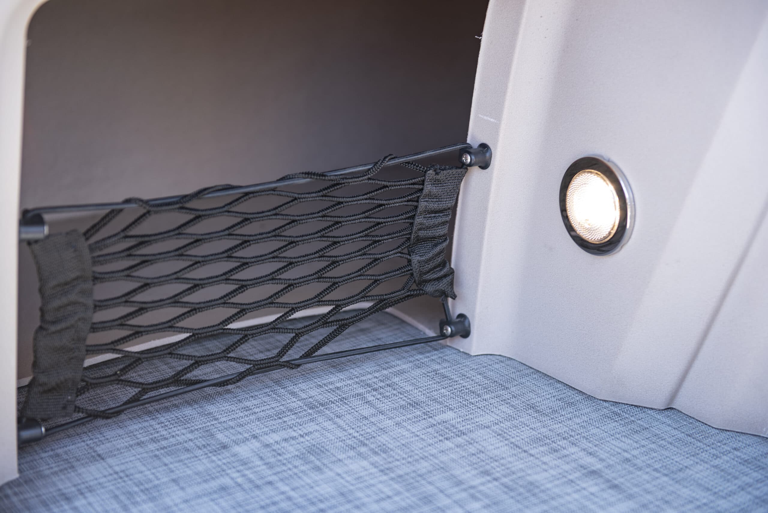 Interior storage net and round light on the side panel of a Princecraft Brio E17 electric boat.