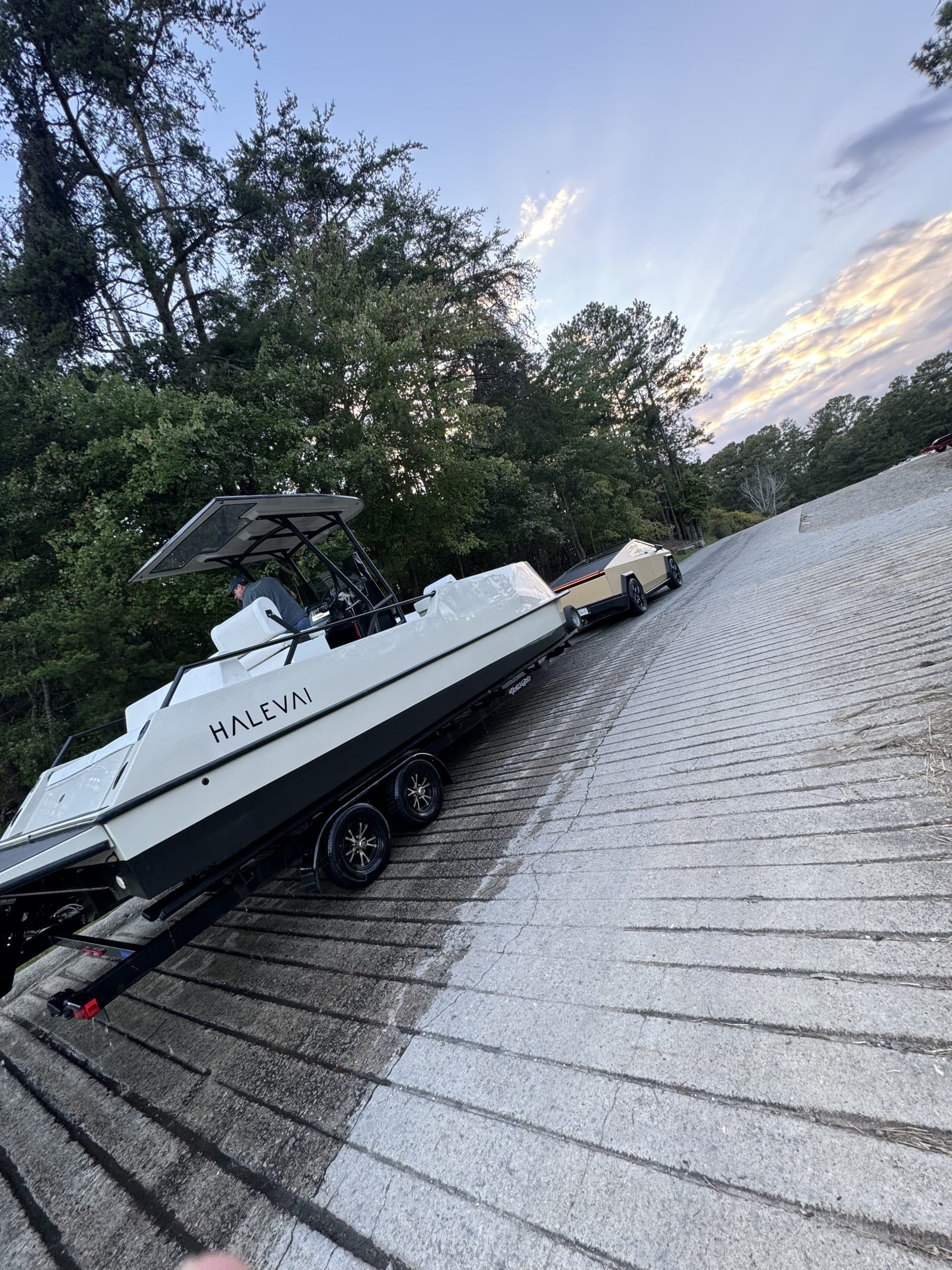 Halevai Model 2050 boat on a trailer, parked on a sloped metal roof beside trees at sunset.