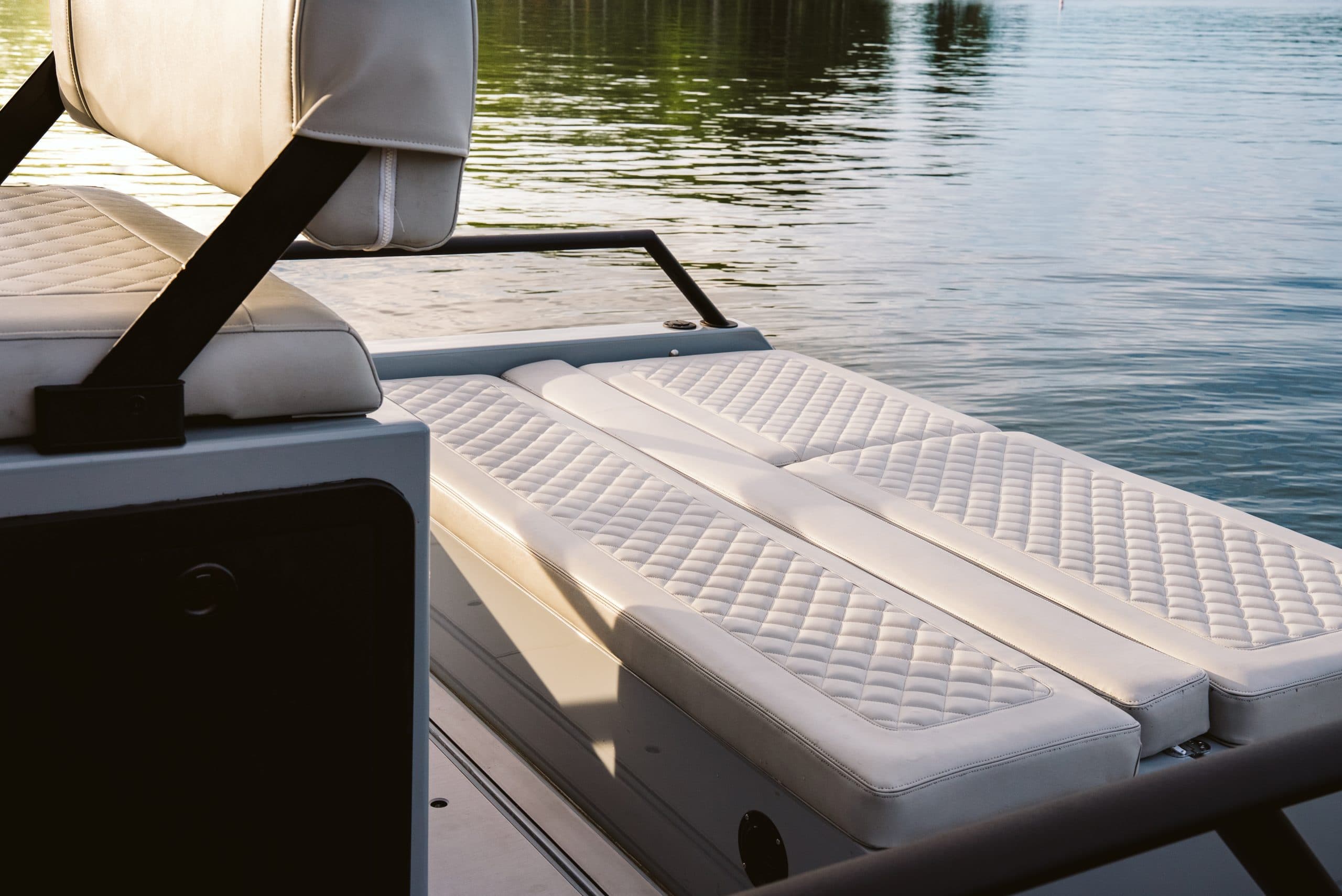 Close-up of Halevai model2050’s cushioned rear seating and sun deck beside calm water.