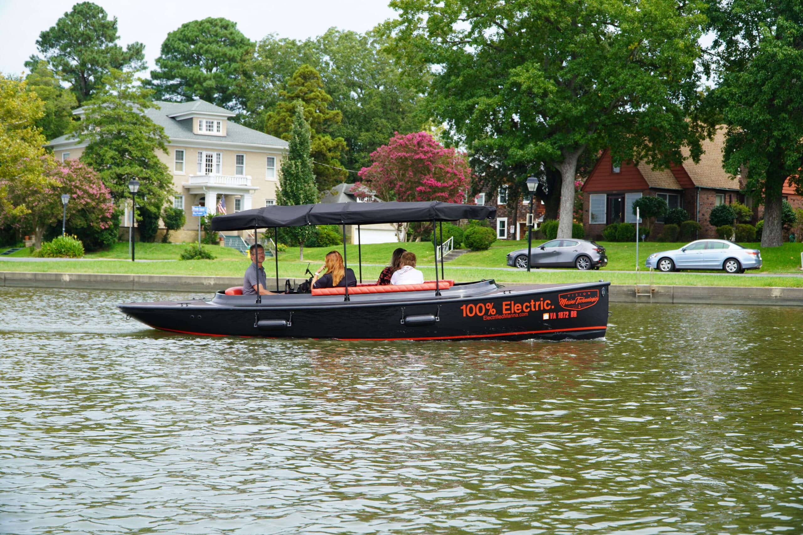 2024 Vision Marine Fantail 217
Side view of a black passenger boat with a canopy cruising on a tree-lined lake; “100% Electric” is visibly marked on the hull.