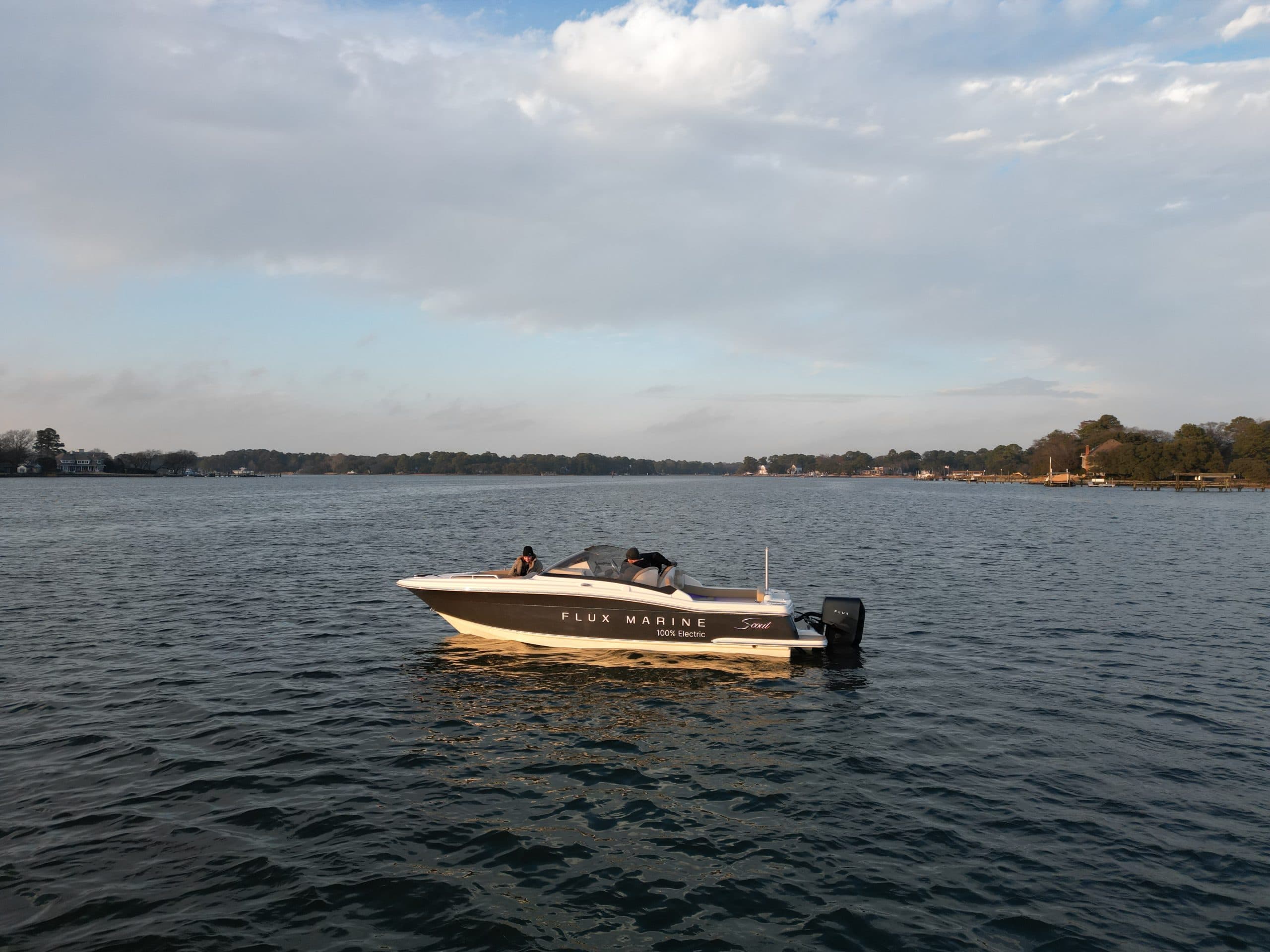 Scout 215 Dorado motorboat on a calm inlet, with wooded shoreline and partly cloudy sky in the background.