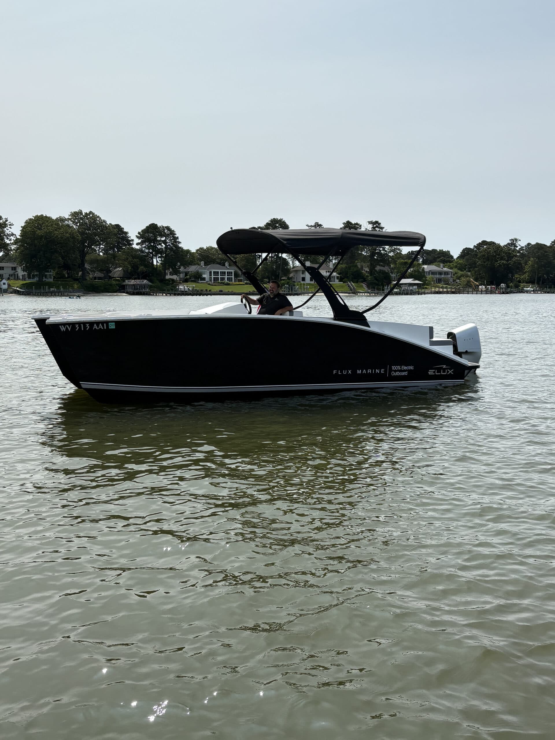 Flux Marine GFX Stealth viewed in profile on the water, showing the hull, canopy, cockpit, and outboard motor.
