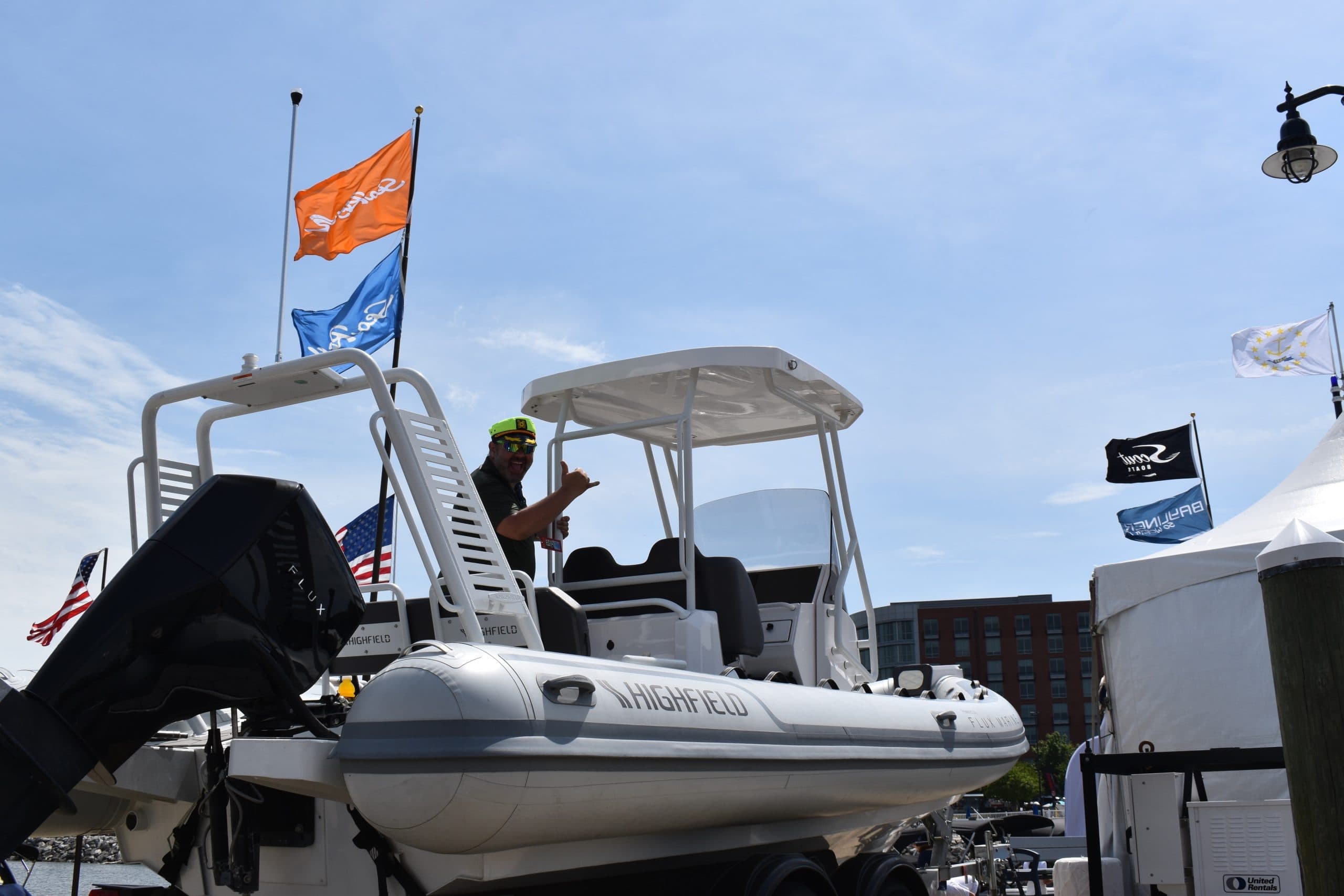 Highfield Sport 660 rigid inflatable boat displayed on a trailer at a marina, with canopy, console, and flags visible.