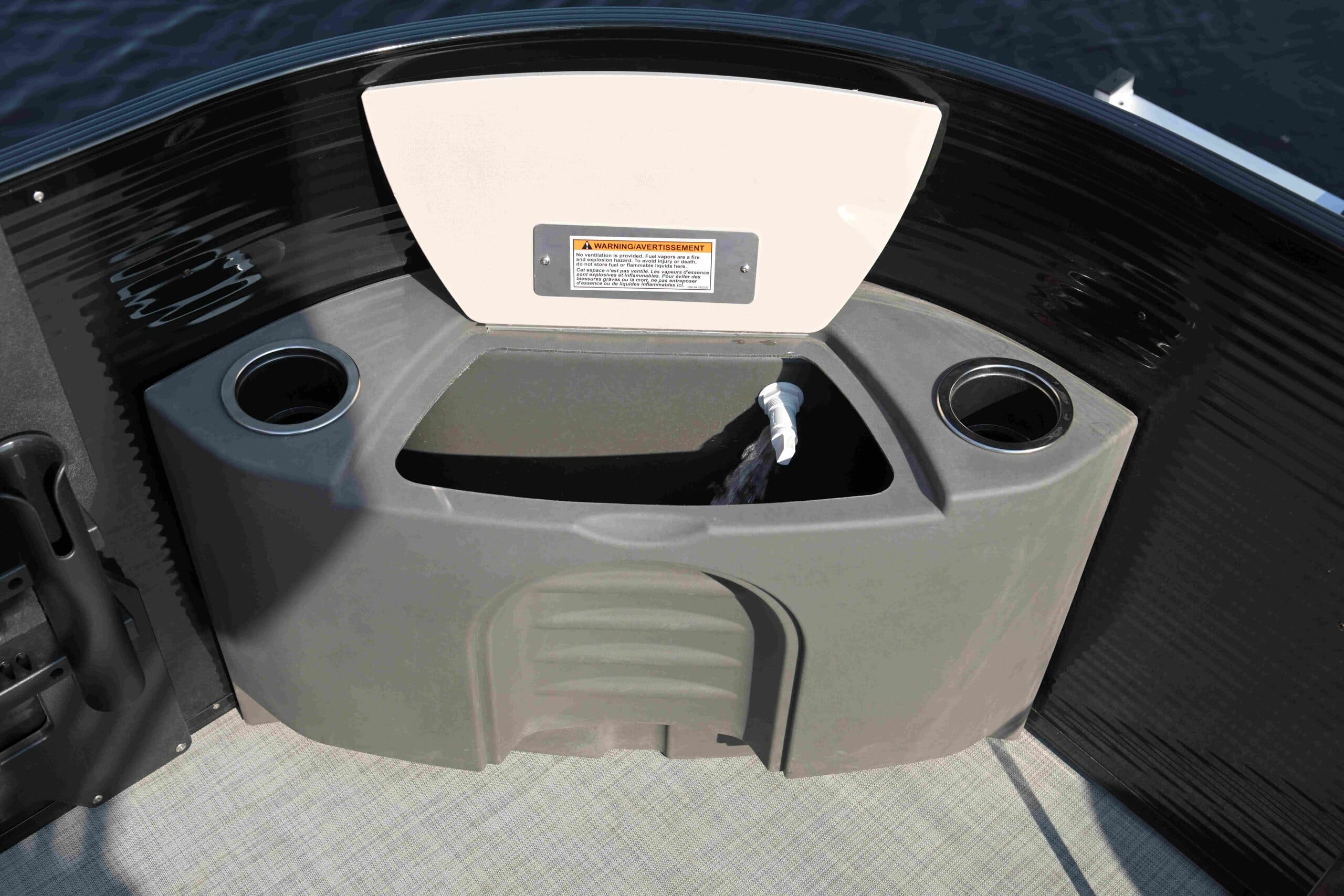 grey storage compartment with cushioned lid lifted opening with, two cup holders on the side, and a central open storage well aboard a Princecraft Brio E17.
