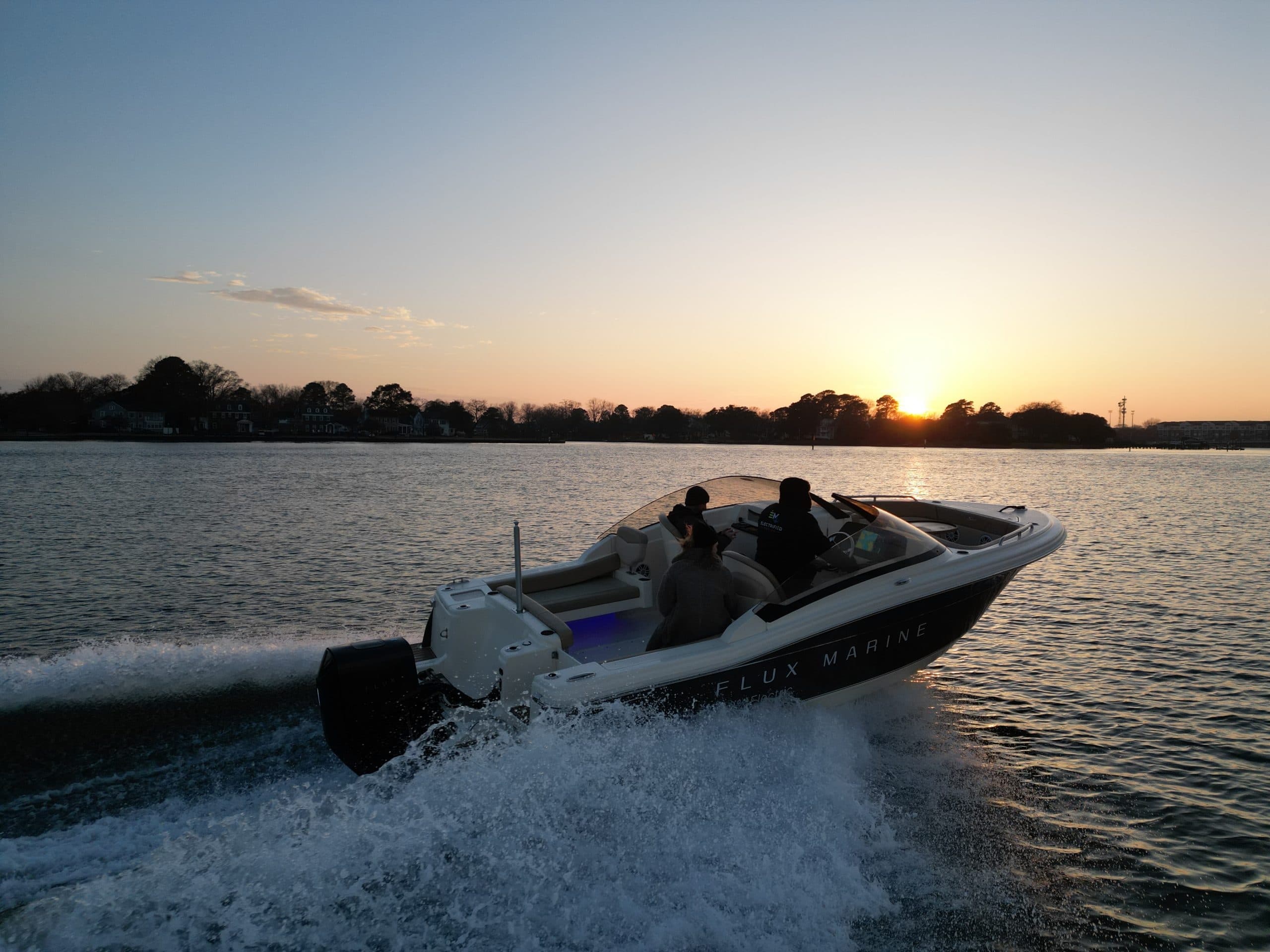 Scout 215 Dorado powerboat speeding across water at sunset, viewed from the side with spray trailing behind.