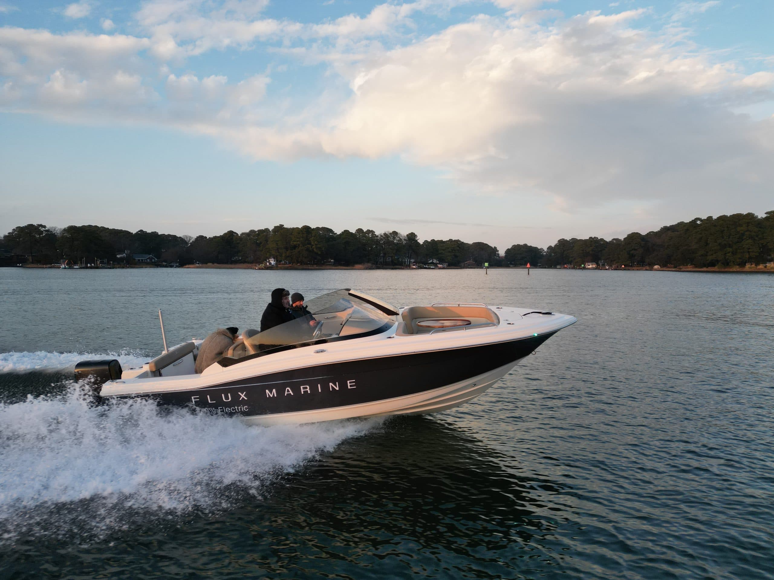 Scout 215 Dorado-style powerboat speeding across a lake, viewed from the side with trees and shoreline in the background.