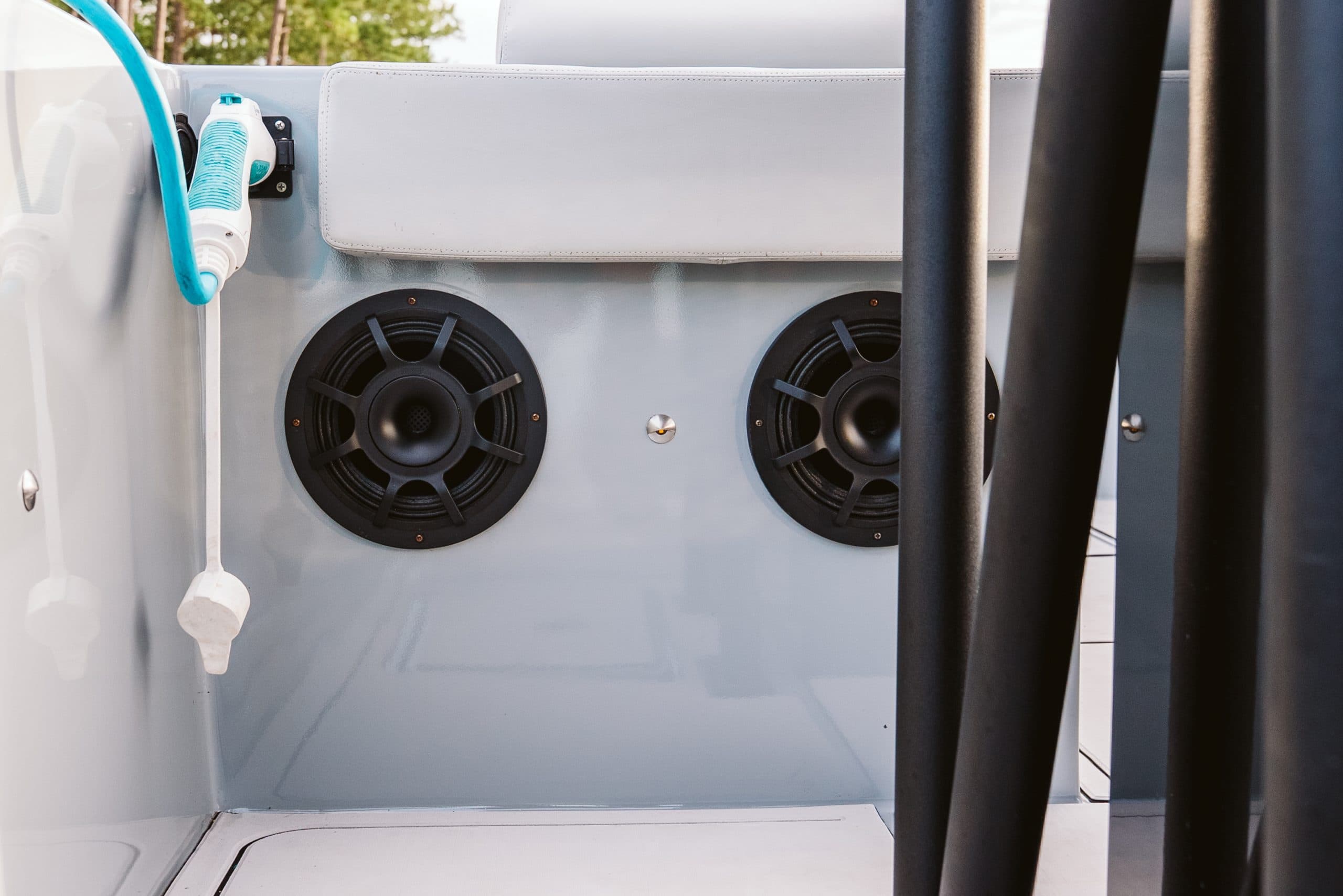 Interior side panel of a Halevai Model 2050 electric boat with two round speakers, a blue cable, and black support rails.
