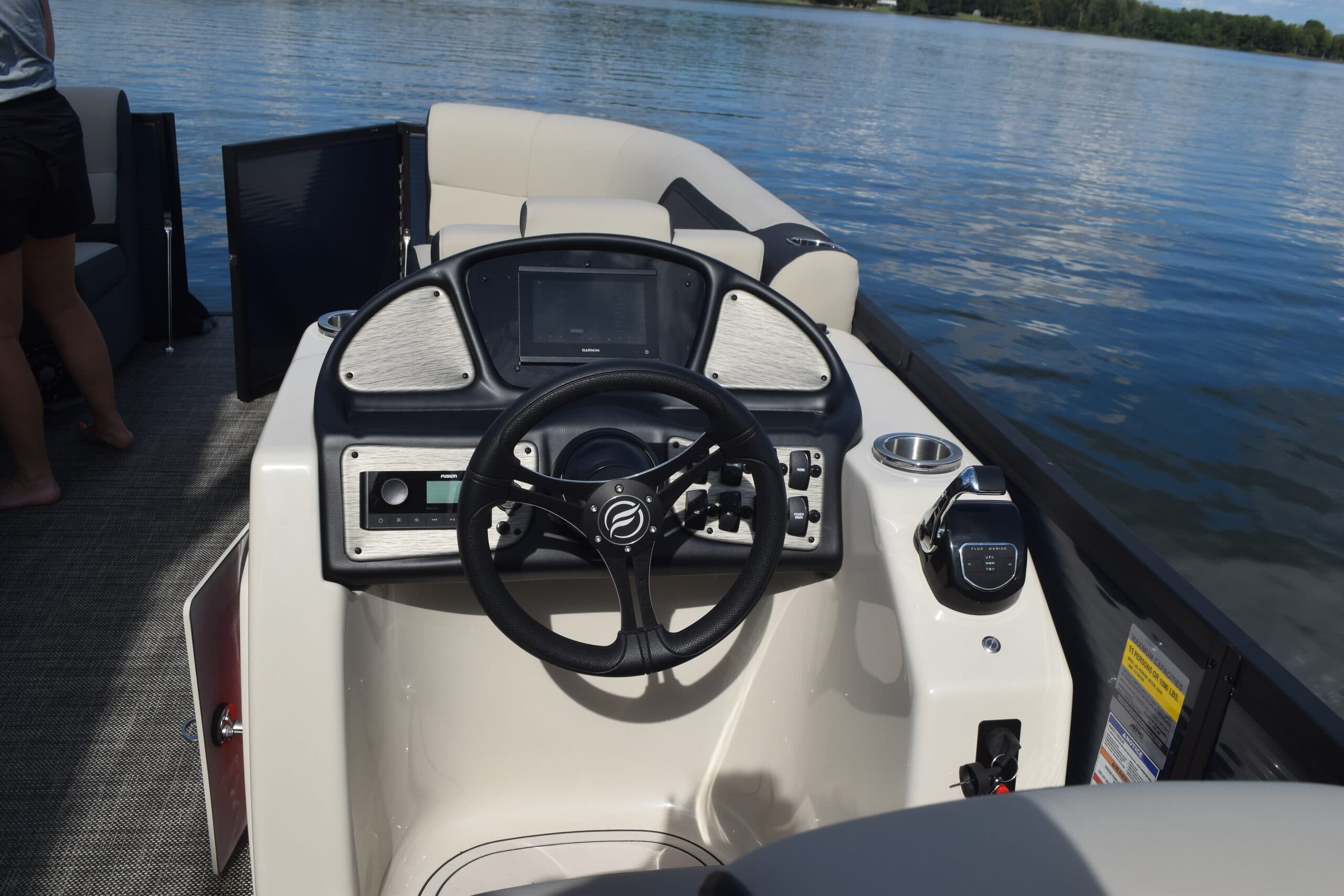 Flux Marine Discover boat helm with steering wheel, dashboard display, controls, and cushioned seating on a calm lake.