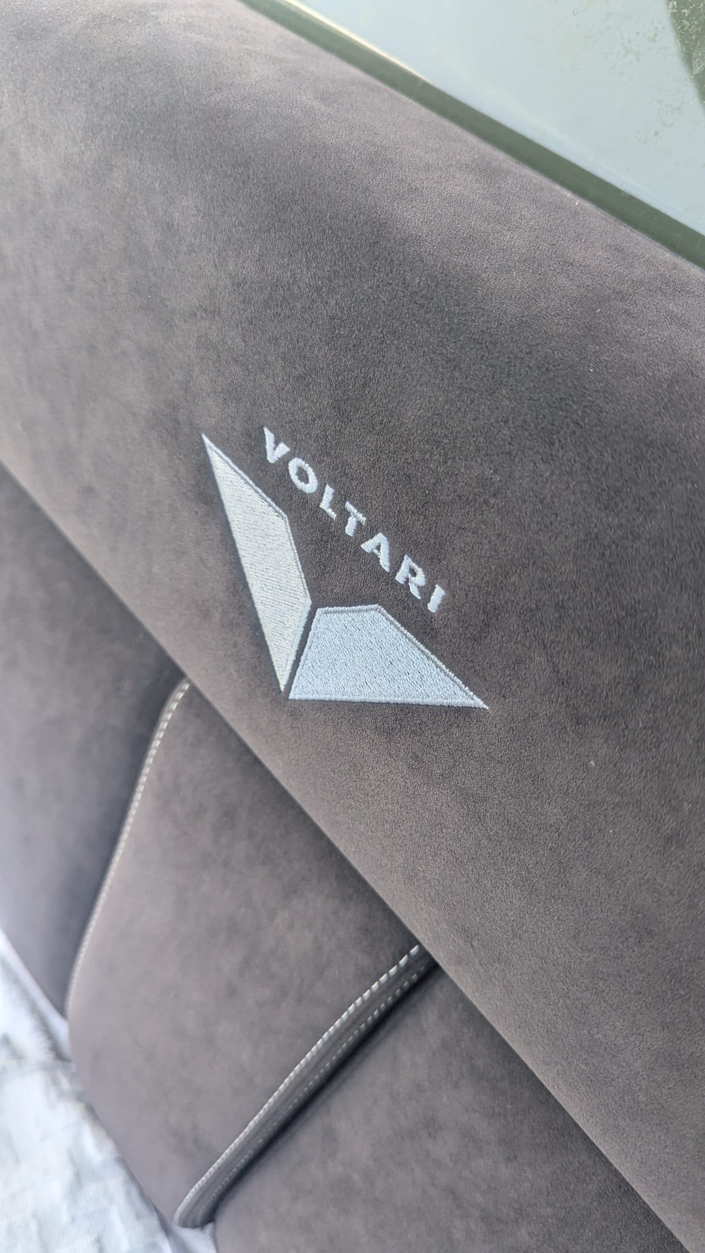 Voltari 260E seat back with Voltari logo, shown in close-up from above.