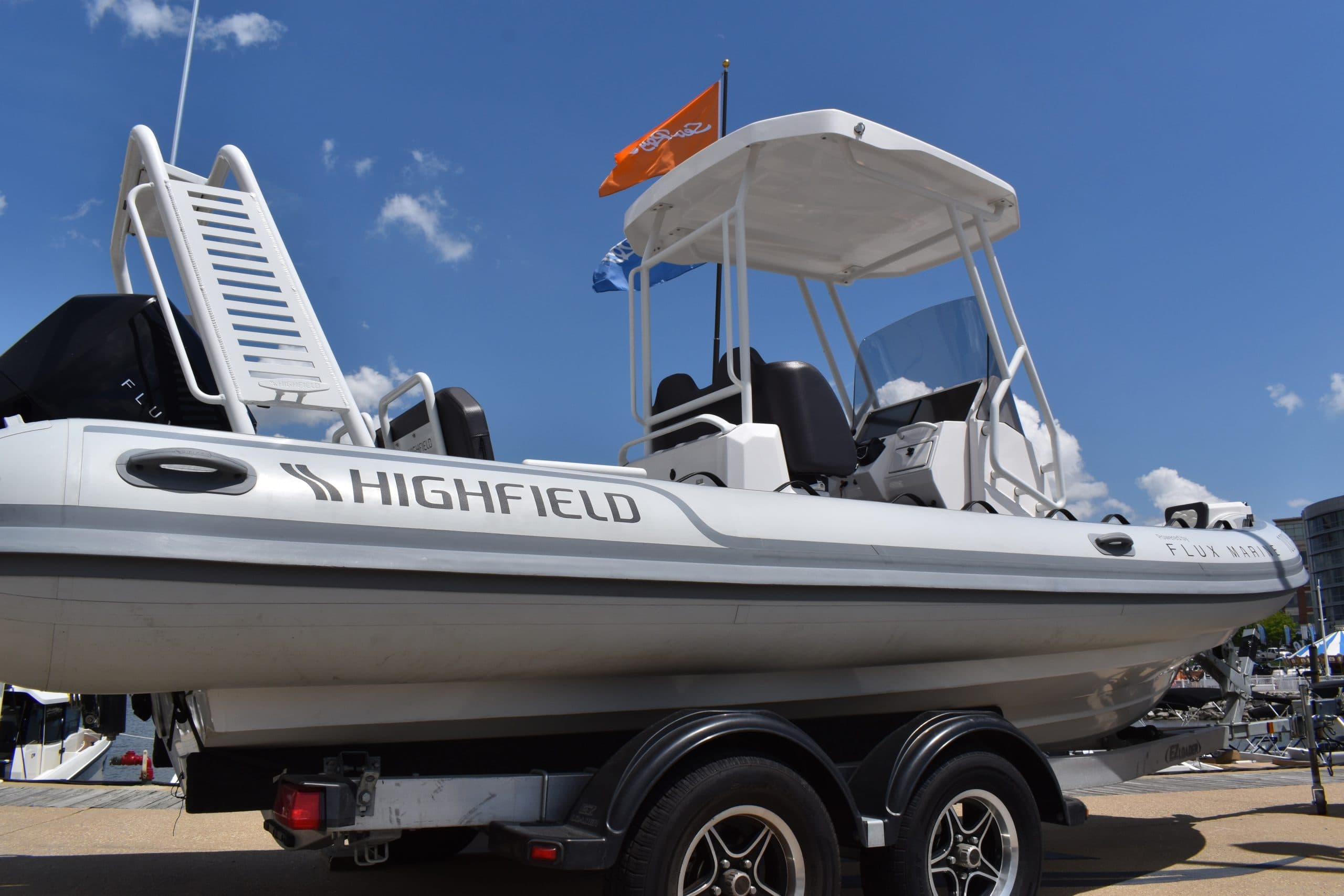 Highfield Sport 660 rigid inflatable boat with center console and T-top on a dual-axle trailer outdoors.