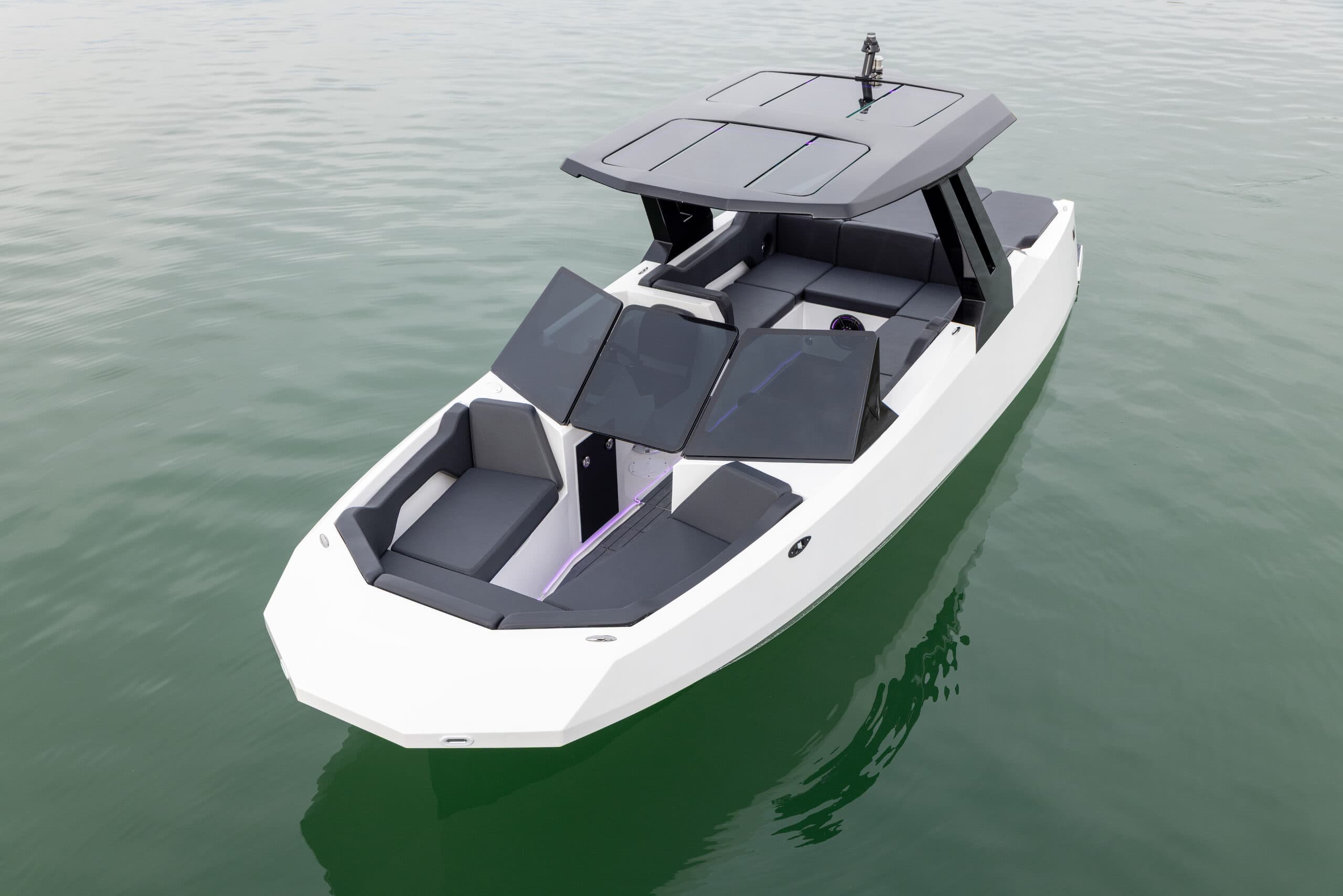 White electric boat (2026 Voltaic AEW24) with multiple solar panels on the roof and bow, viewed from above on calm water.