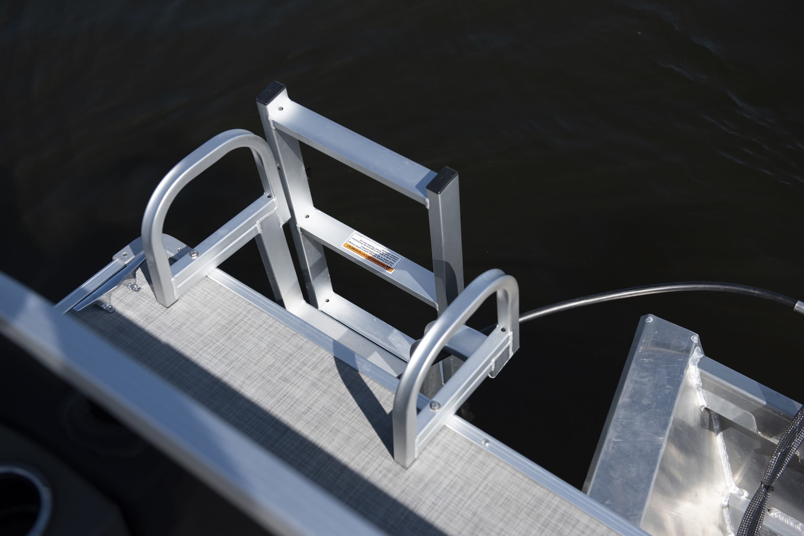 Stainless steel swim ladder and railings on a 2026 Princecraft Brio e 17 pontoon electric boat over dark water.