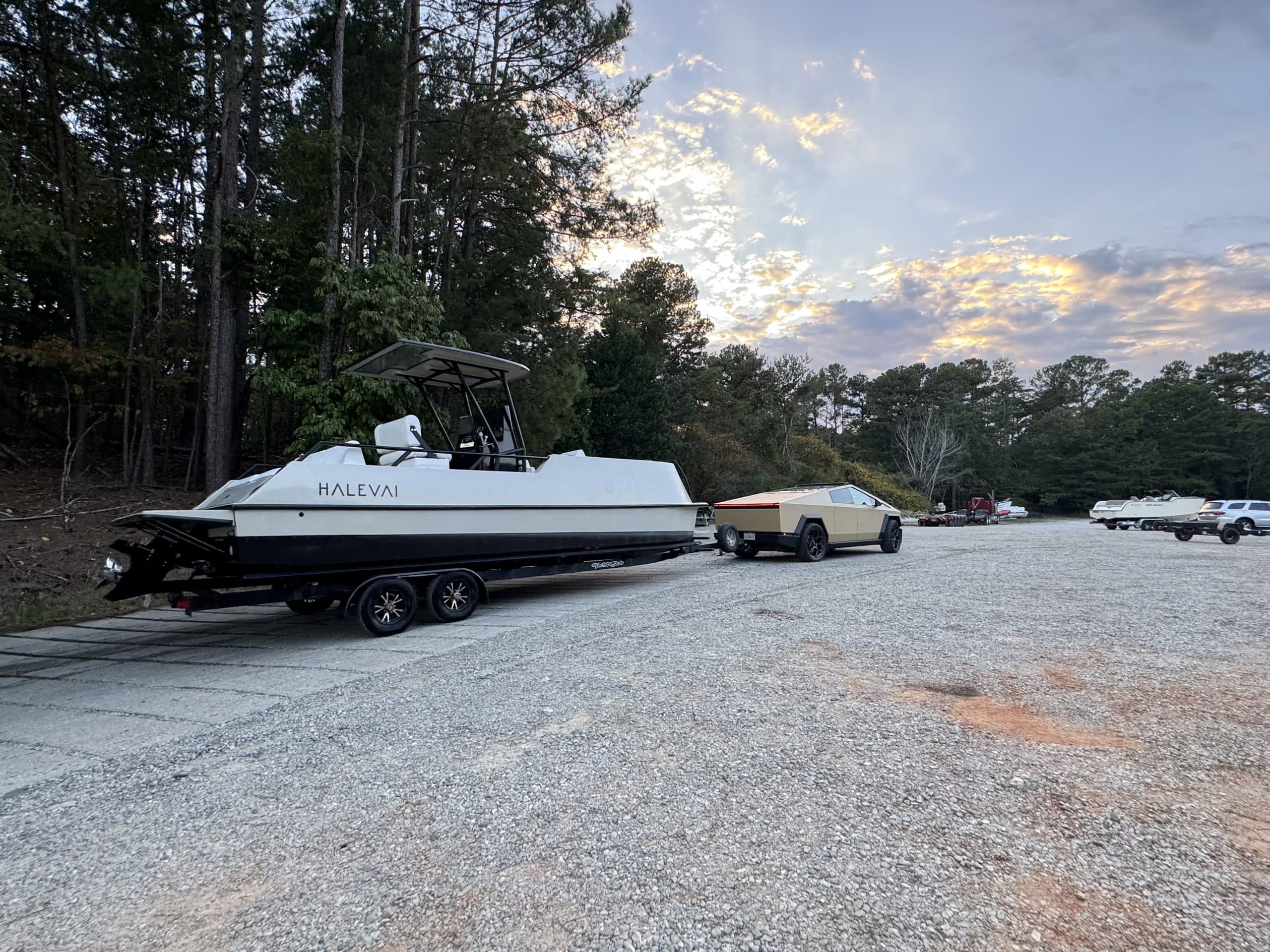 Halevai model2050 boat on a trailer in a gravel marina lot at sunset, with trees and other boats in the background.