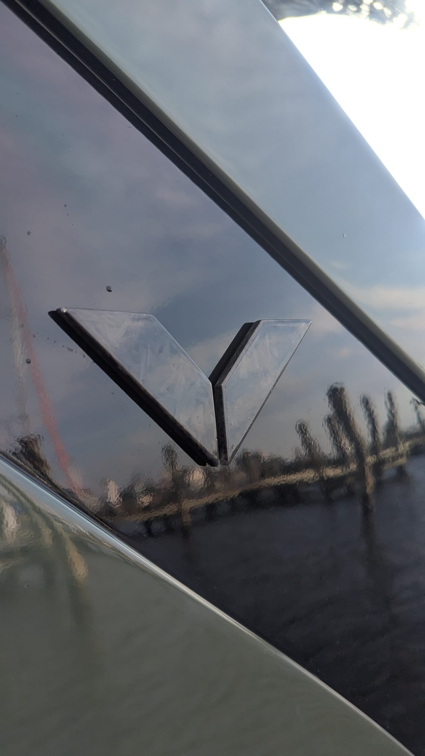 Voltari 260E windshield and wiper detail, viewed from outside with reflections of the sky and shoreline.
