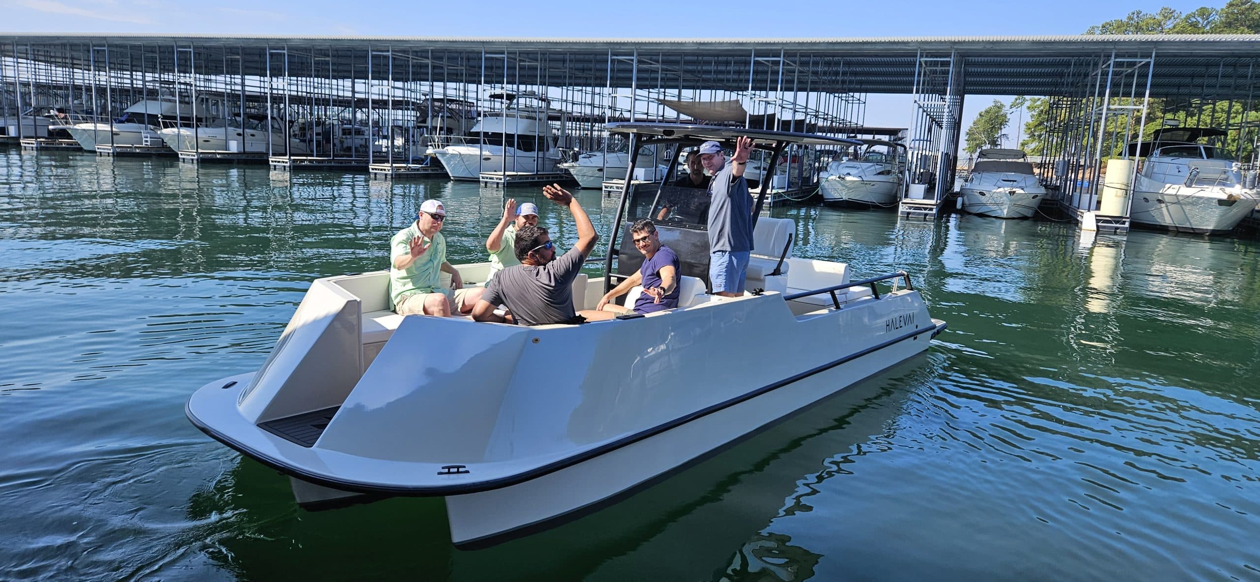 Halevai Model 2050 electric boat carrying  6 passengers through a marina, with covered boat slips and moored vessels in the background.