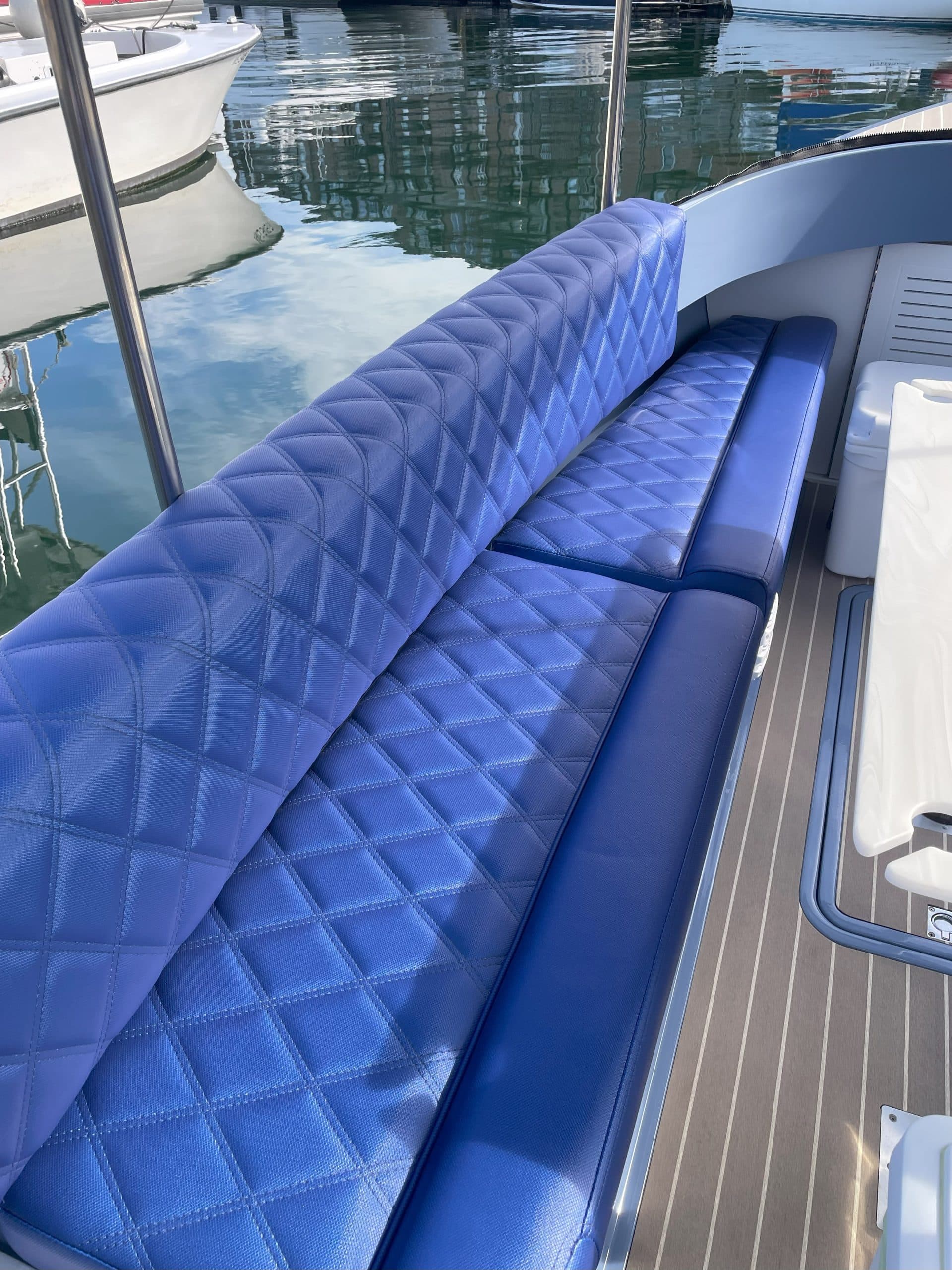 Vision Marine Fantail 217 with blue quilted bench seating along the interior of the boat, with marina water and neighboring boats visible beyond.