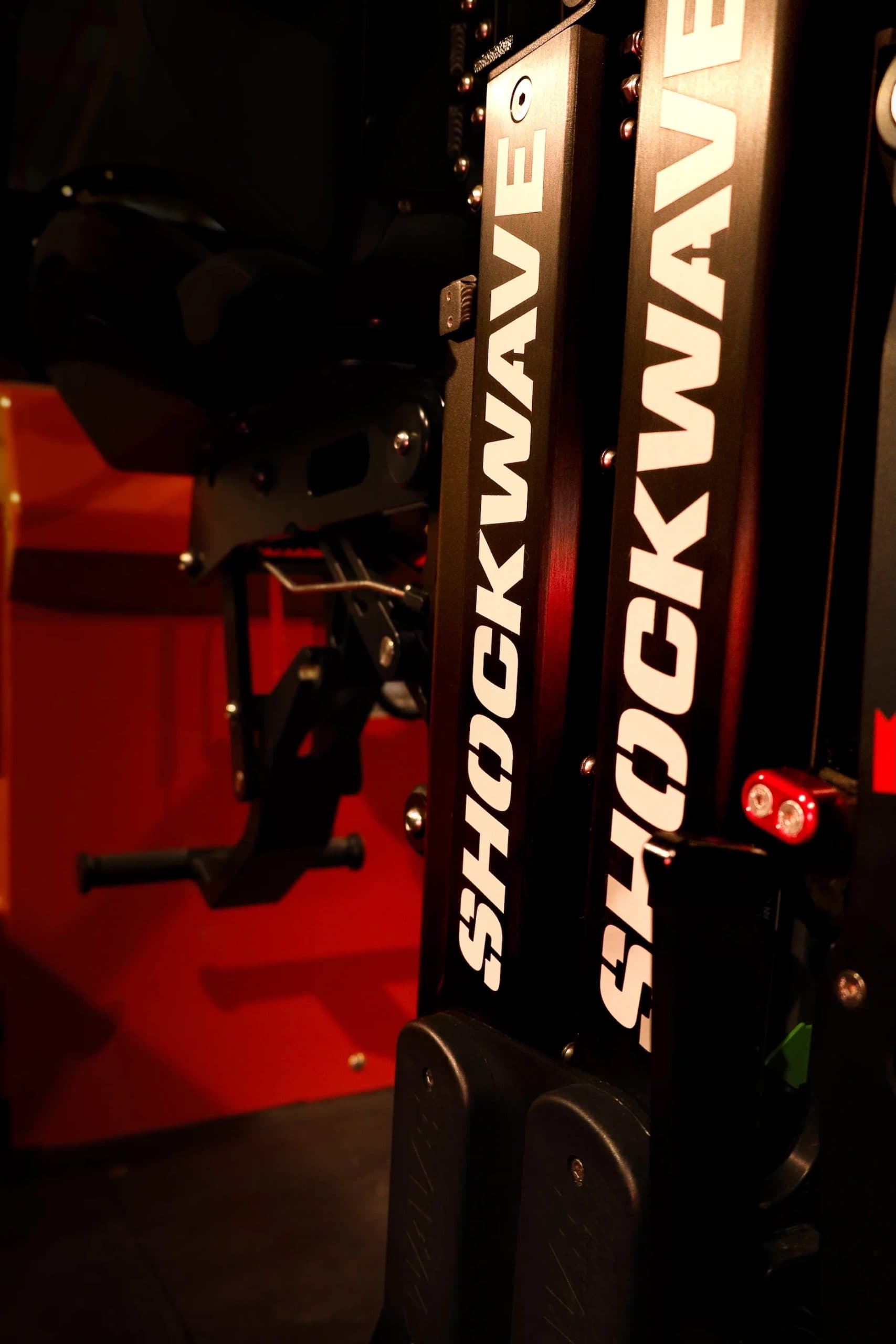 Close up of interior of boat with red carpet and Shockwave written on side of black helm