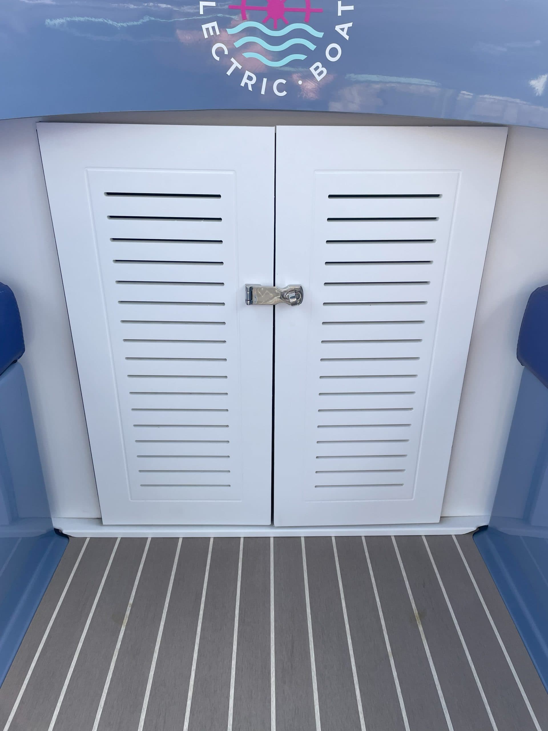 Vision Marine Fantail 217 white louvered storage compartment doors with a central latch on the rear deck of an electric boat.
