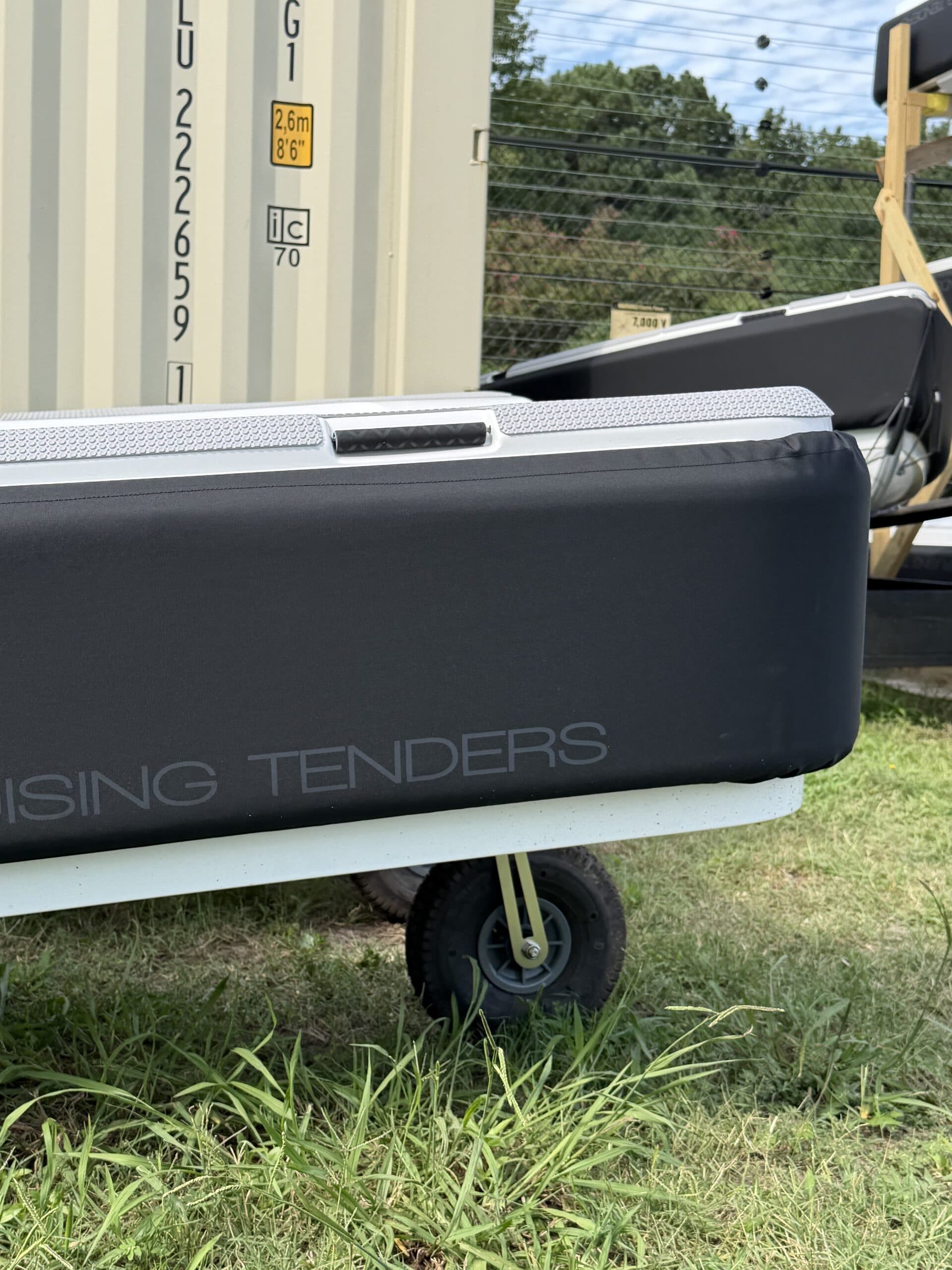 Close side view of an Offshore Cruising Tenders inflatable tender on a trailer, showing its hull, rub rail, side handle, and wheel.