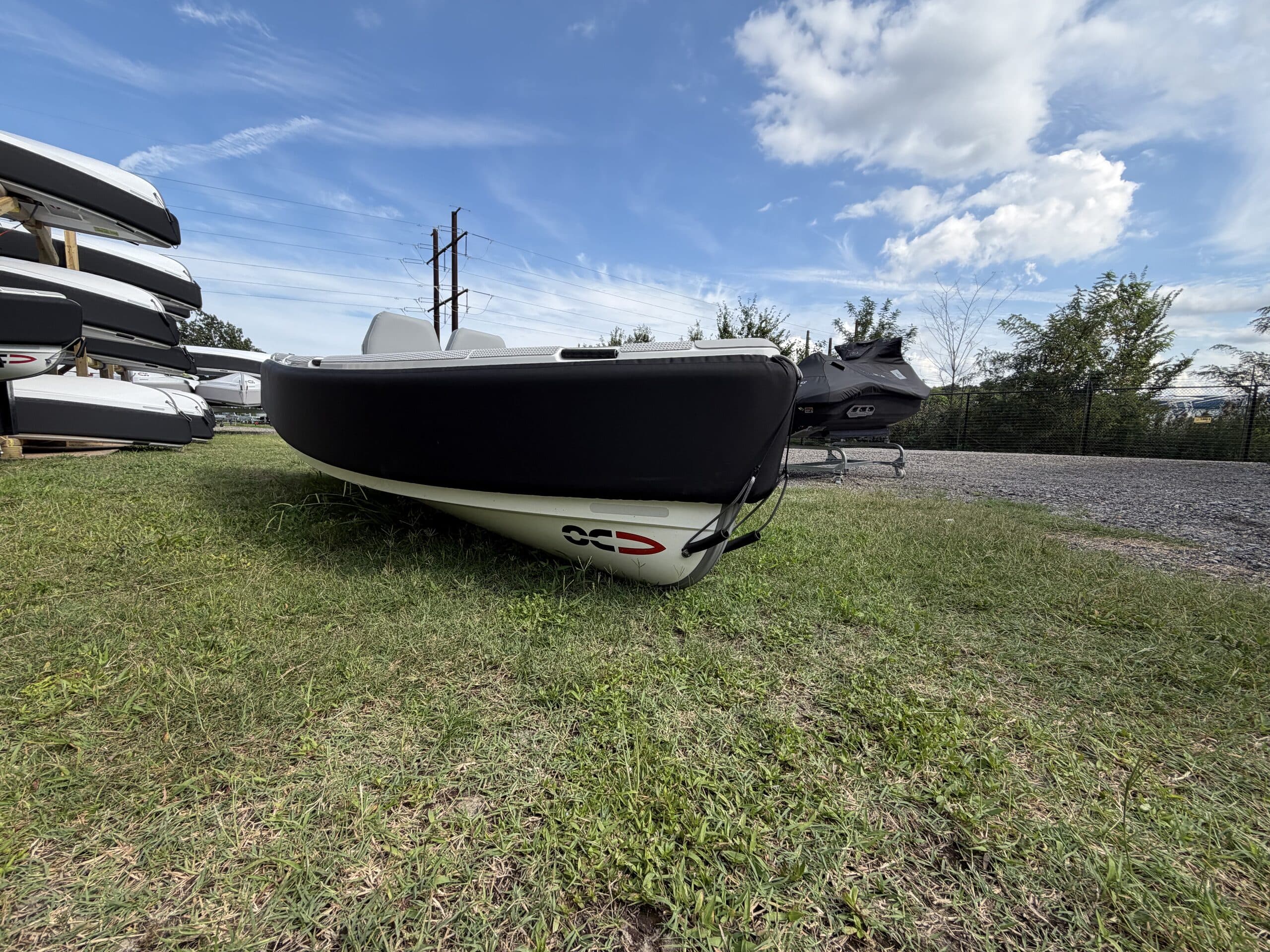 2026 Offshore Cruising Tenders OC300 tender viewed from the bow on a grassy lot, showing its dark hull, white lower hull, and covered center console.