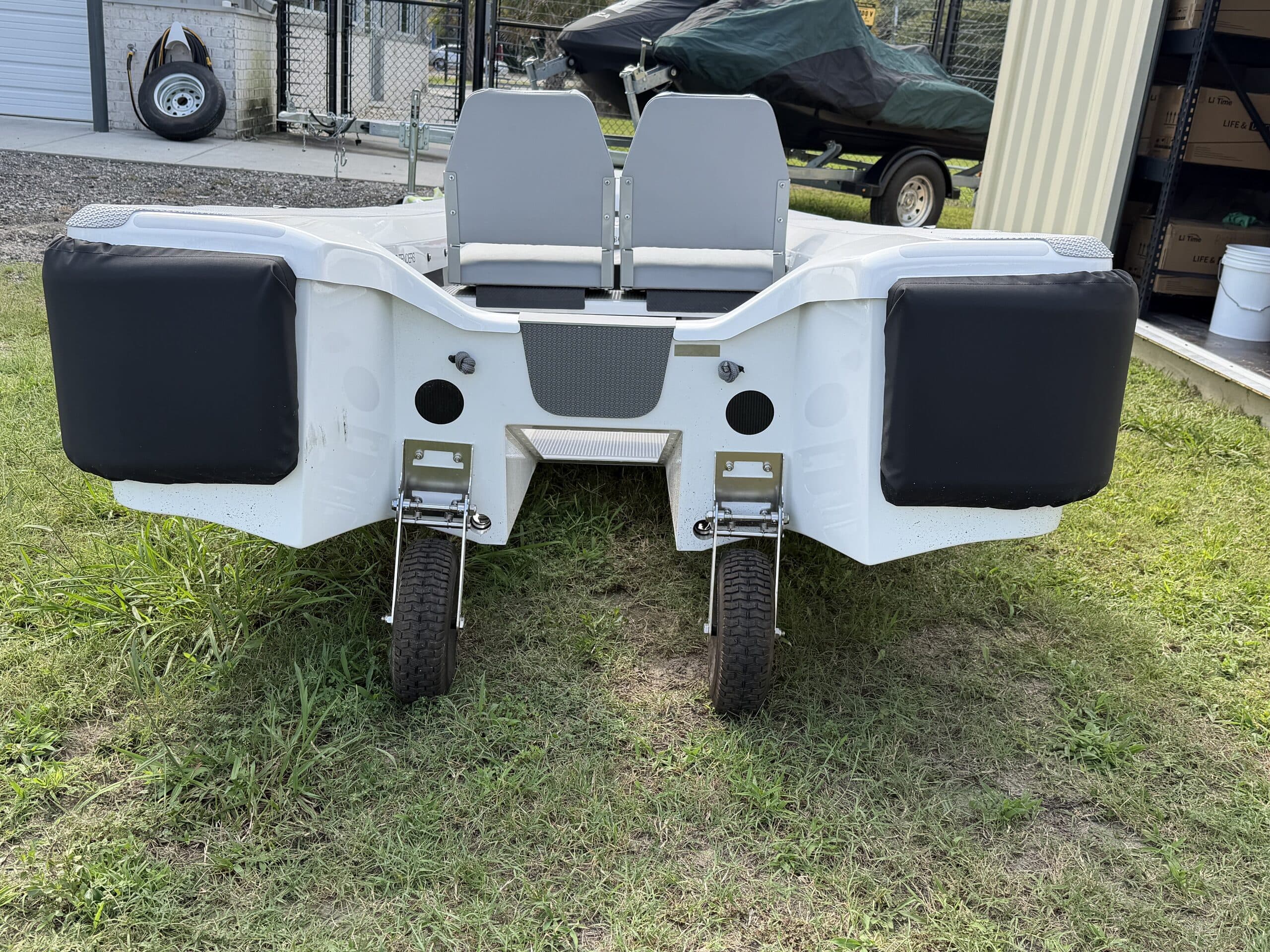 Rear view of a compact white 2026 Offshore Cruising Tenders OC300 showing twin seats, two wheels, black side pontoons, and an open central hull area.