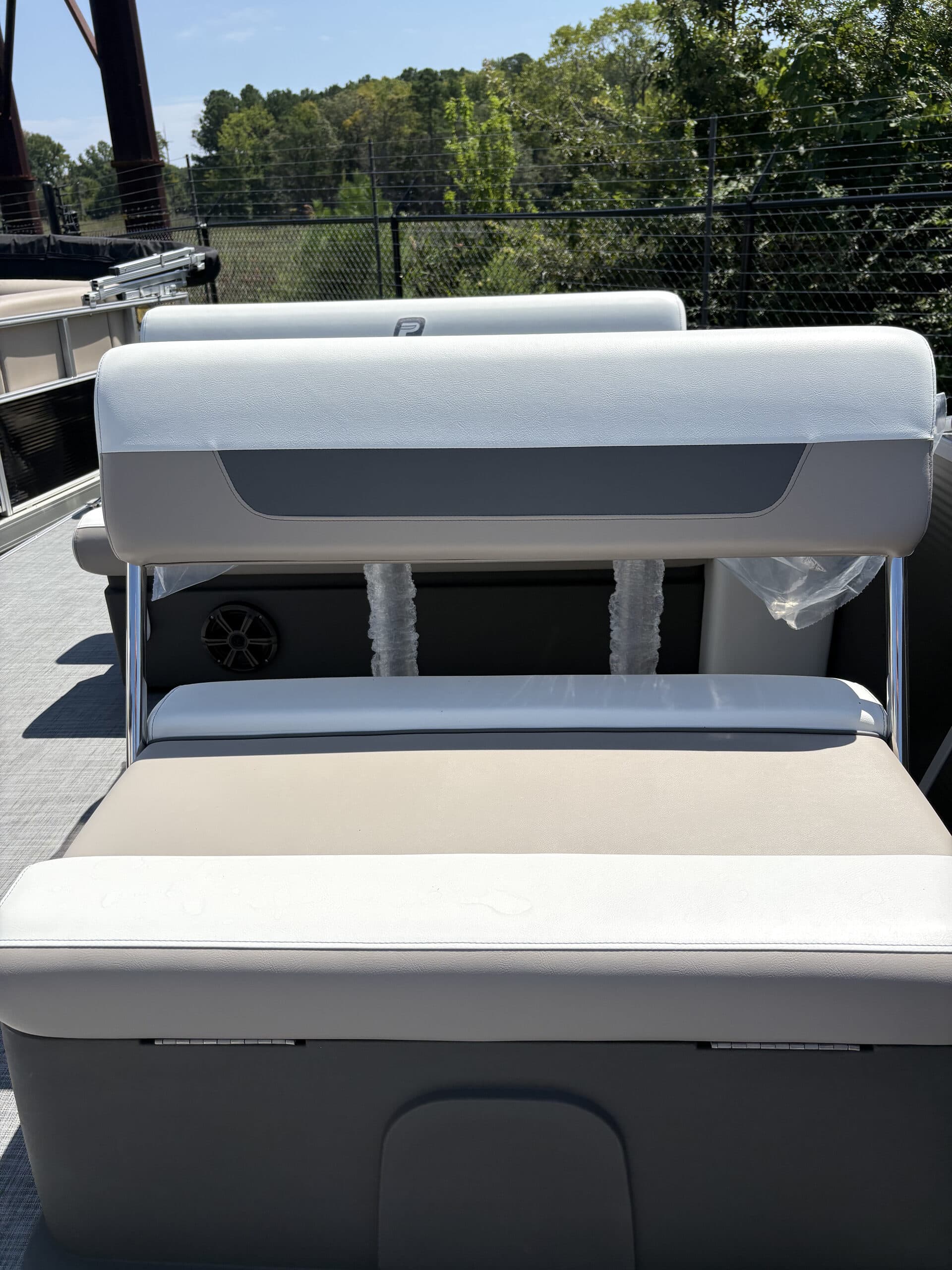 Rear-facing view of a pontoon boat’s (2026 Princecraft Vectra 21 RL) aft seating, showing a cushioned bench, rear sun pad, and storage compartment.