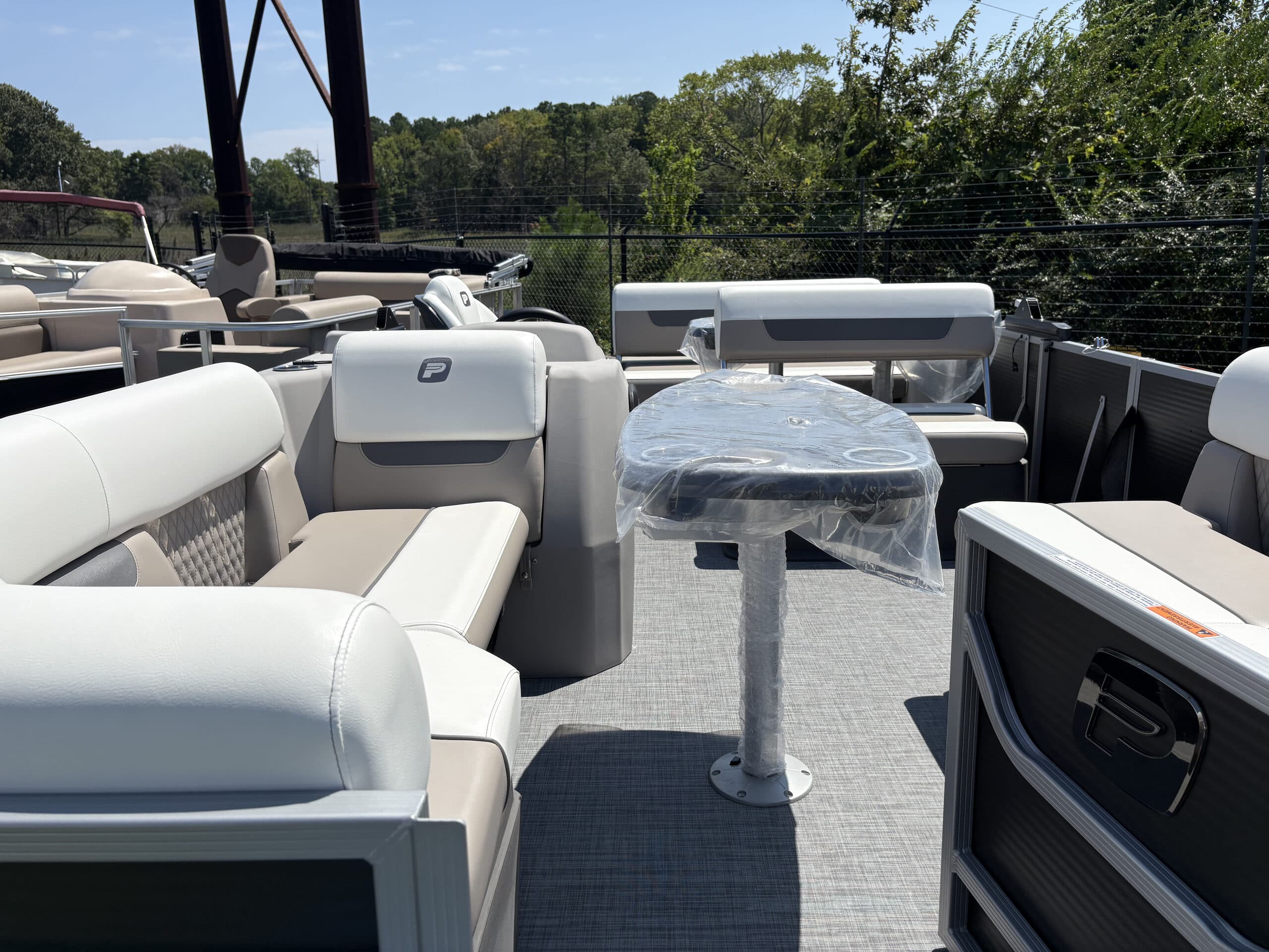 View from the bow into the pontoon boat (2026 Princecraft Vectra 21 RL) cockpit, showing upholstered seating, a table, helm console, and covered deck.