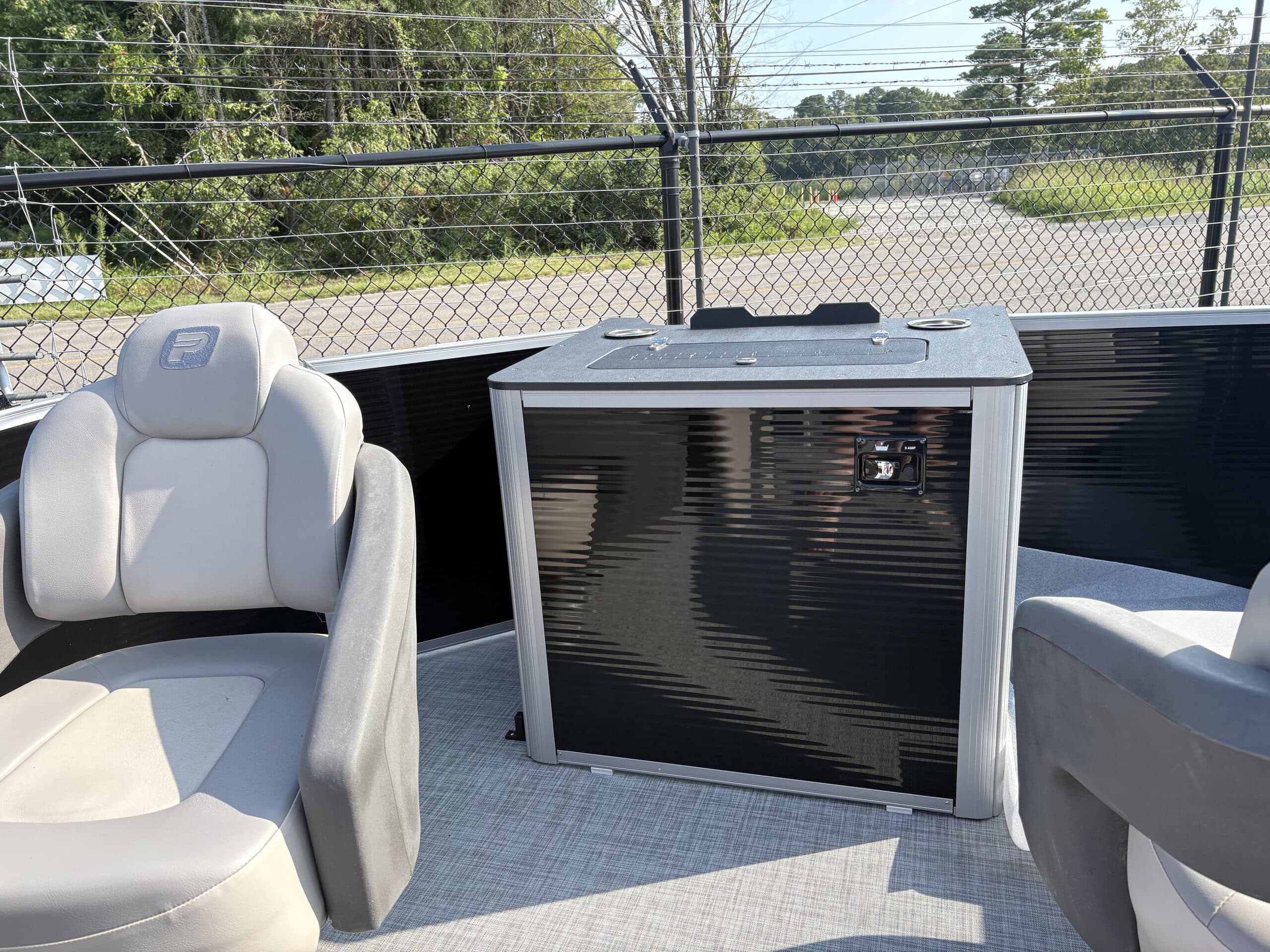 Rear cockpit view of a pontoon boat (2026 Princecraft Jazz 19 4s) showing cushioned seating and a central storage cabinet.