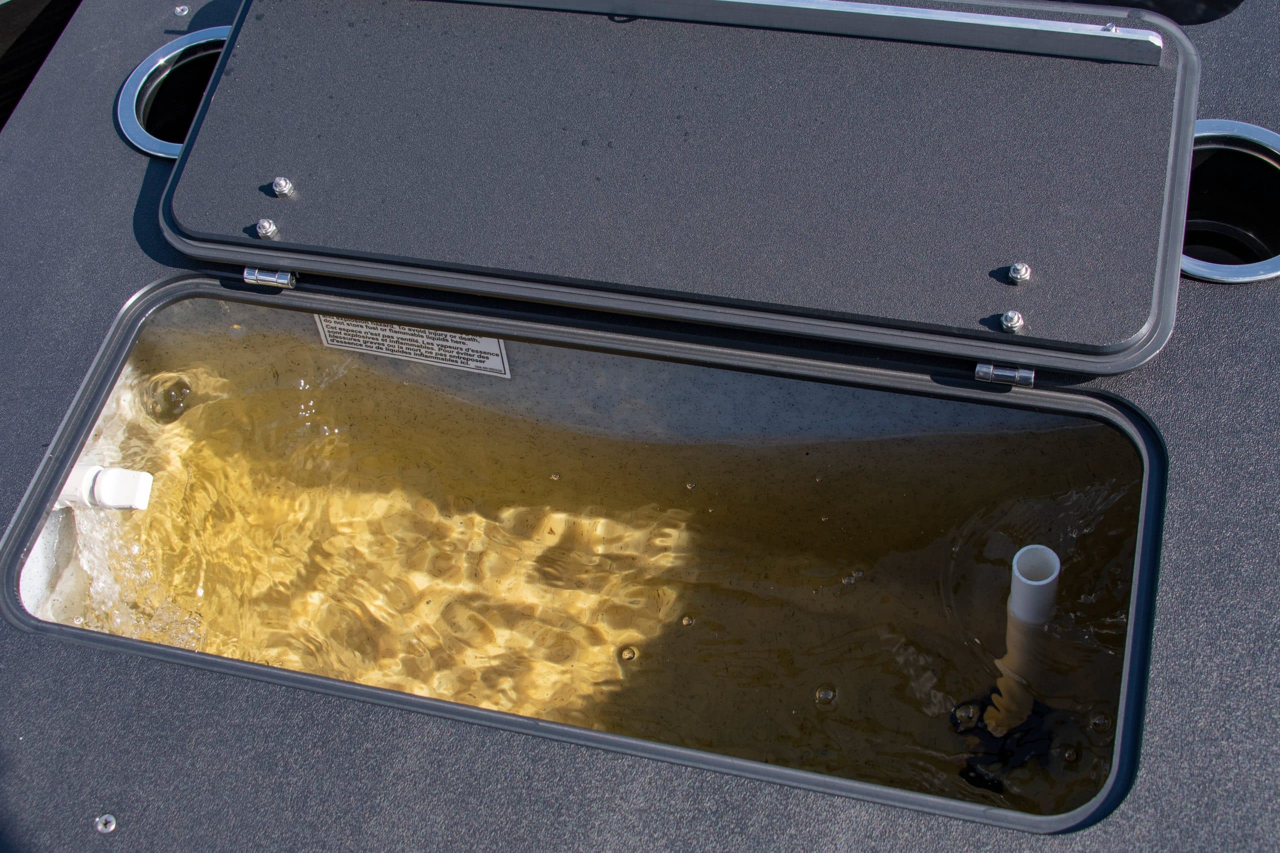 Open storage compartment in the 2026 Princecraft Jazz 19 4s' deck, viewed from above, with water visible inside.