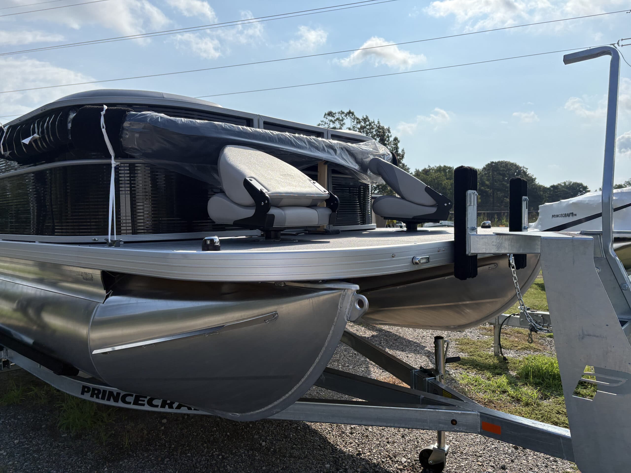 Side view of a 2026 Princecraft Jazz 19 4s on a trailer, showing the bow, pontoons, raised canopy, and seating on deck folded