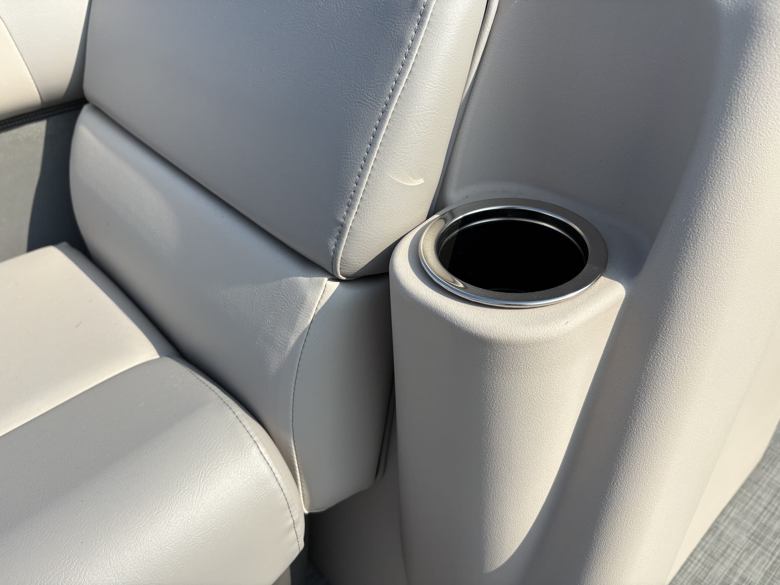 Close-up of a light-gray boat (2026 Princecraft Jazz 19 4s) seat and built-in cup holder, viewed from above at an angle.