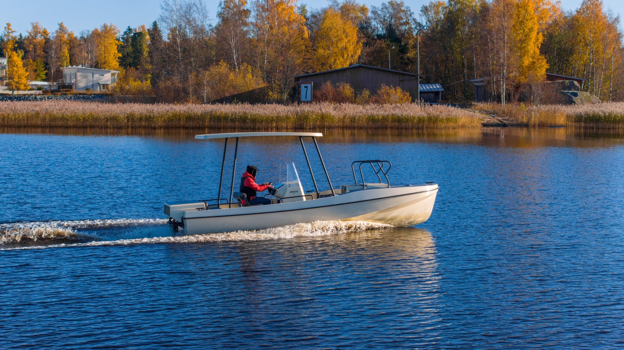Elvene Amber cruising across a lake, viewed from the side with a person seated at the helm.
