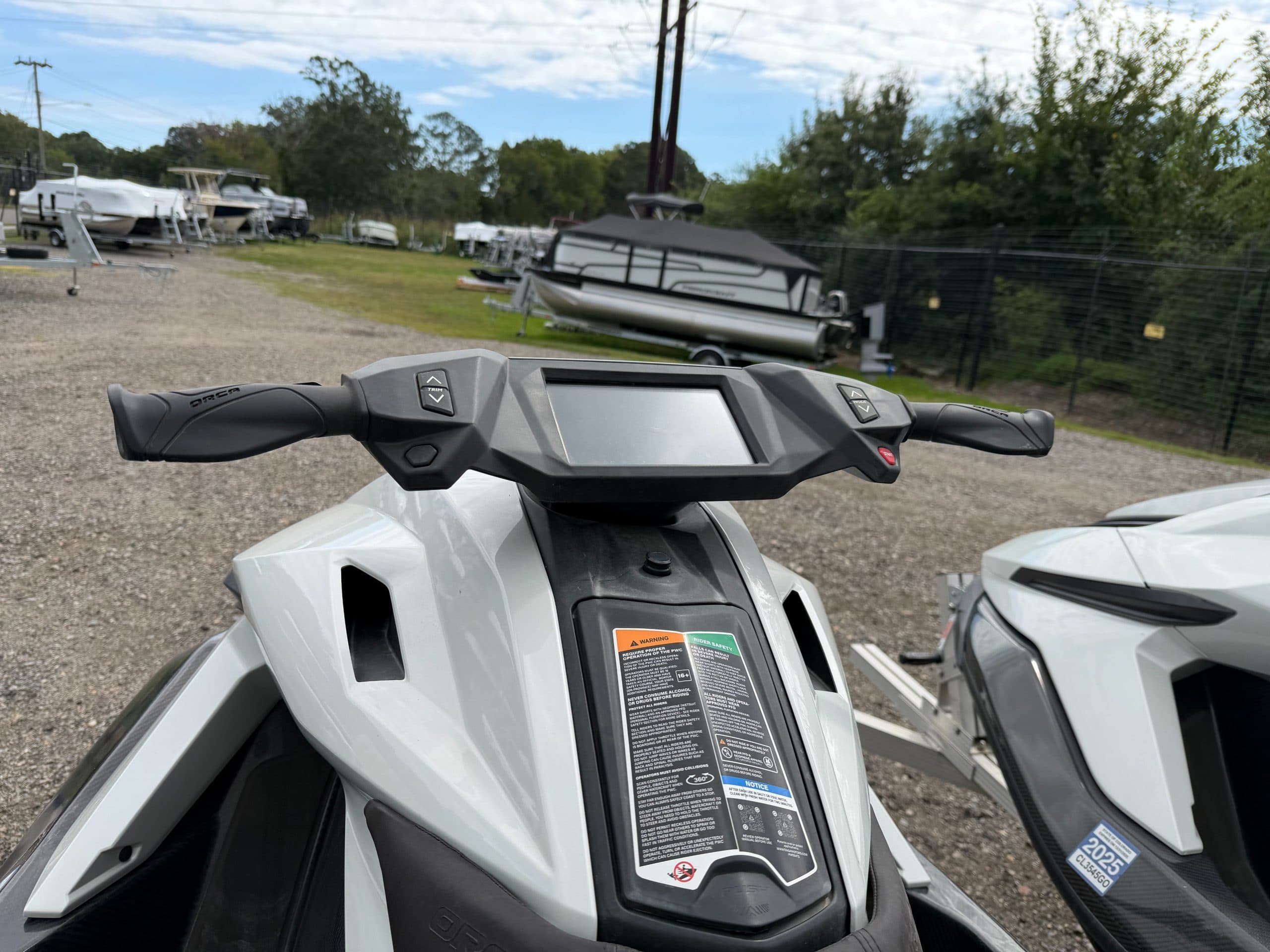 Close view from above of the front console and handlebars of a Taiga Orca personal watercraft, with adjacent watercraft visible.