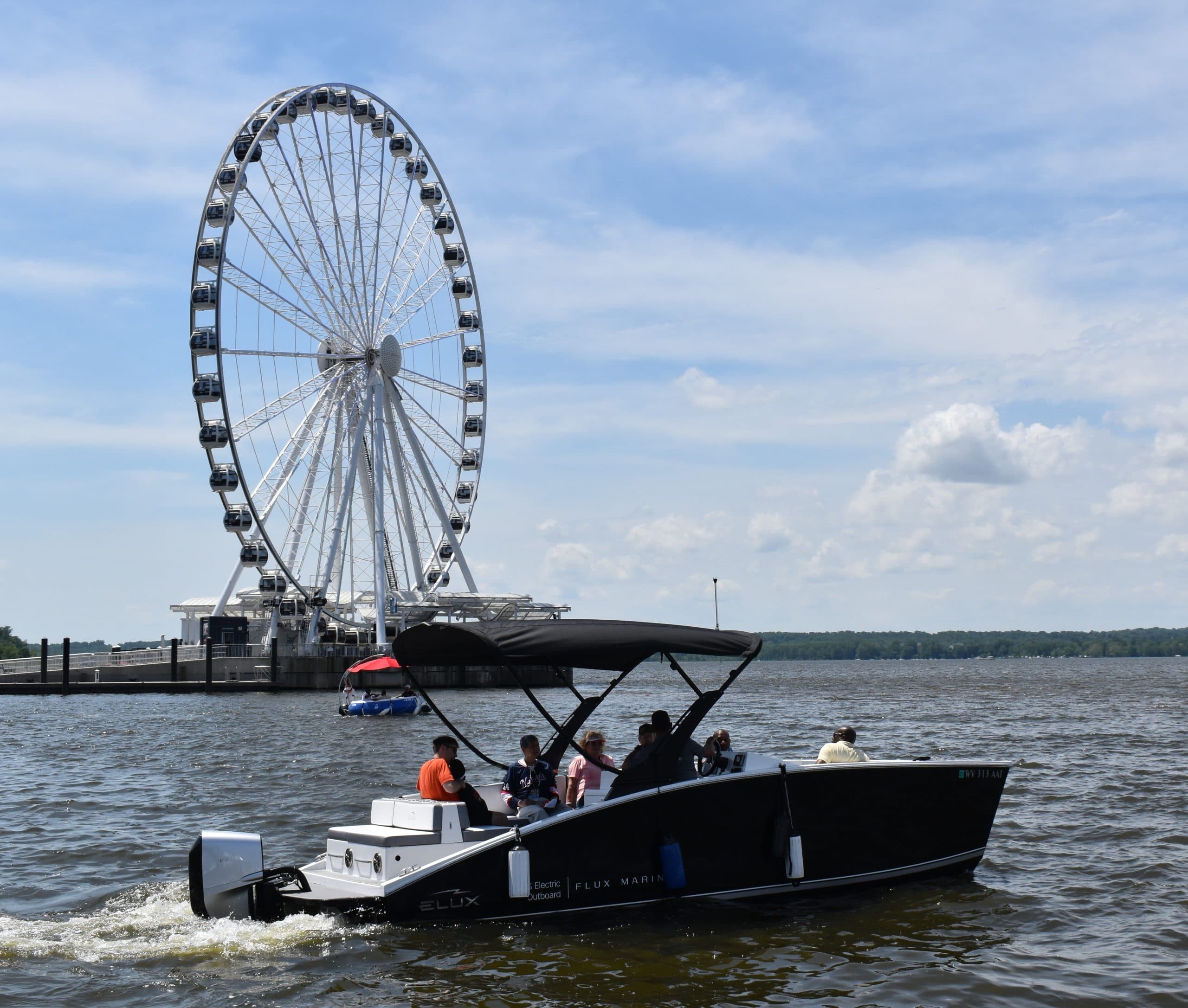 Flux Marine GFX Stealth motorboat viewed from the side on the water near a waterfront Ferris wheel