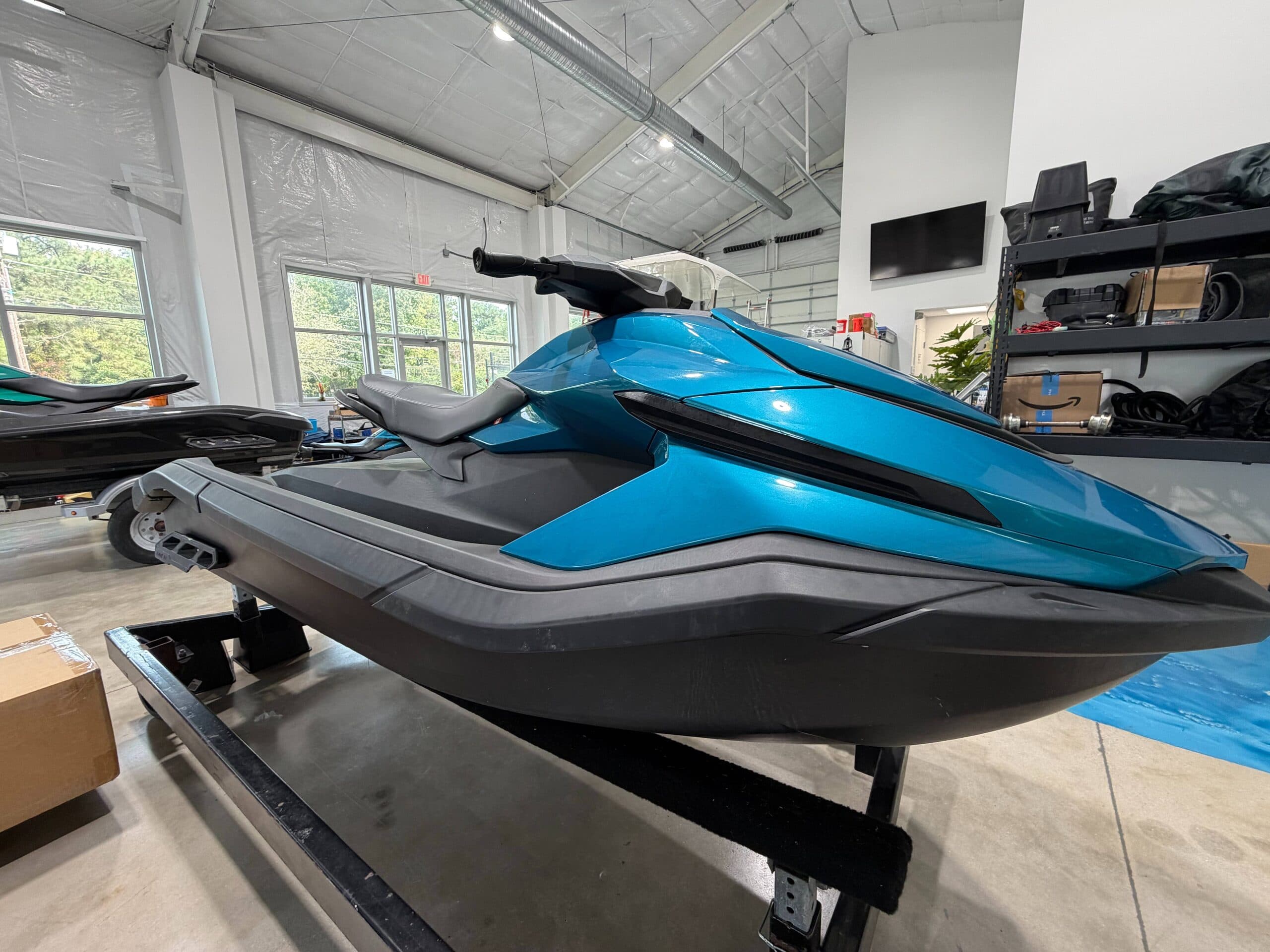 Side view of a blue personal watercraft on a display stand inside a showroom.