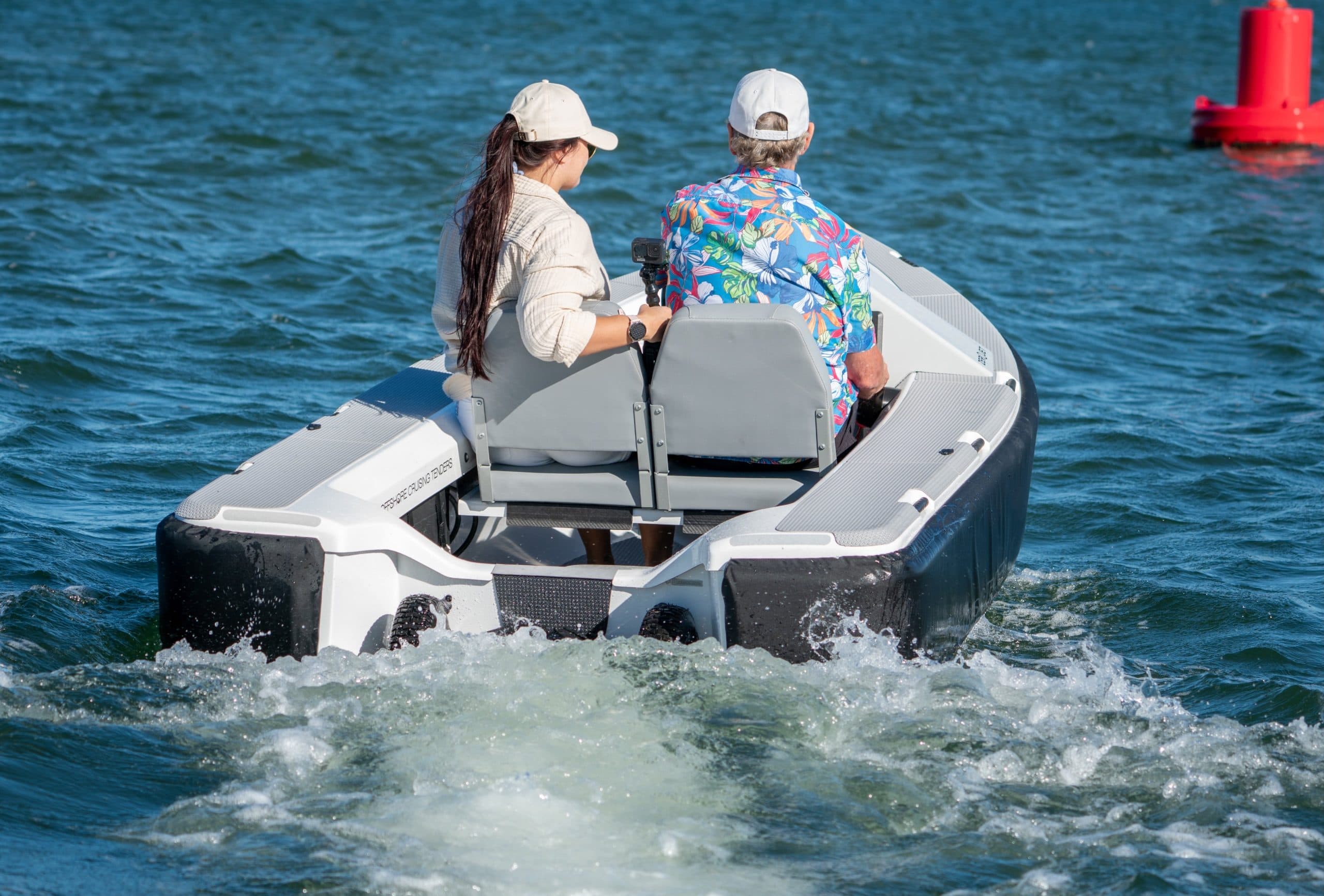 Offshore Cruising Tenders OC330 underway, viewed from the stern with two passengers seated in the aft cockpit.