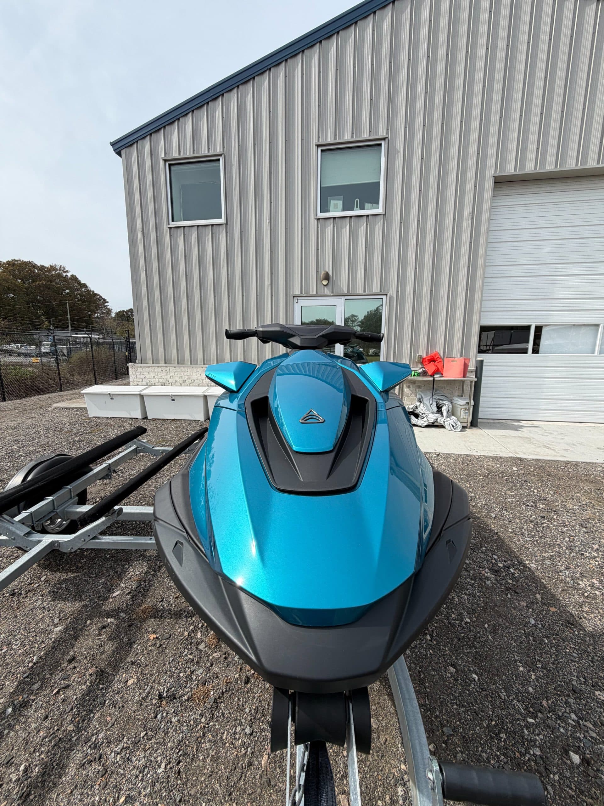 Front view of a blue personal watercraft on a trailer, showing the bow, handlebars, and front storage area.