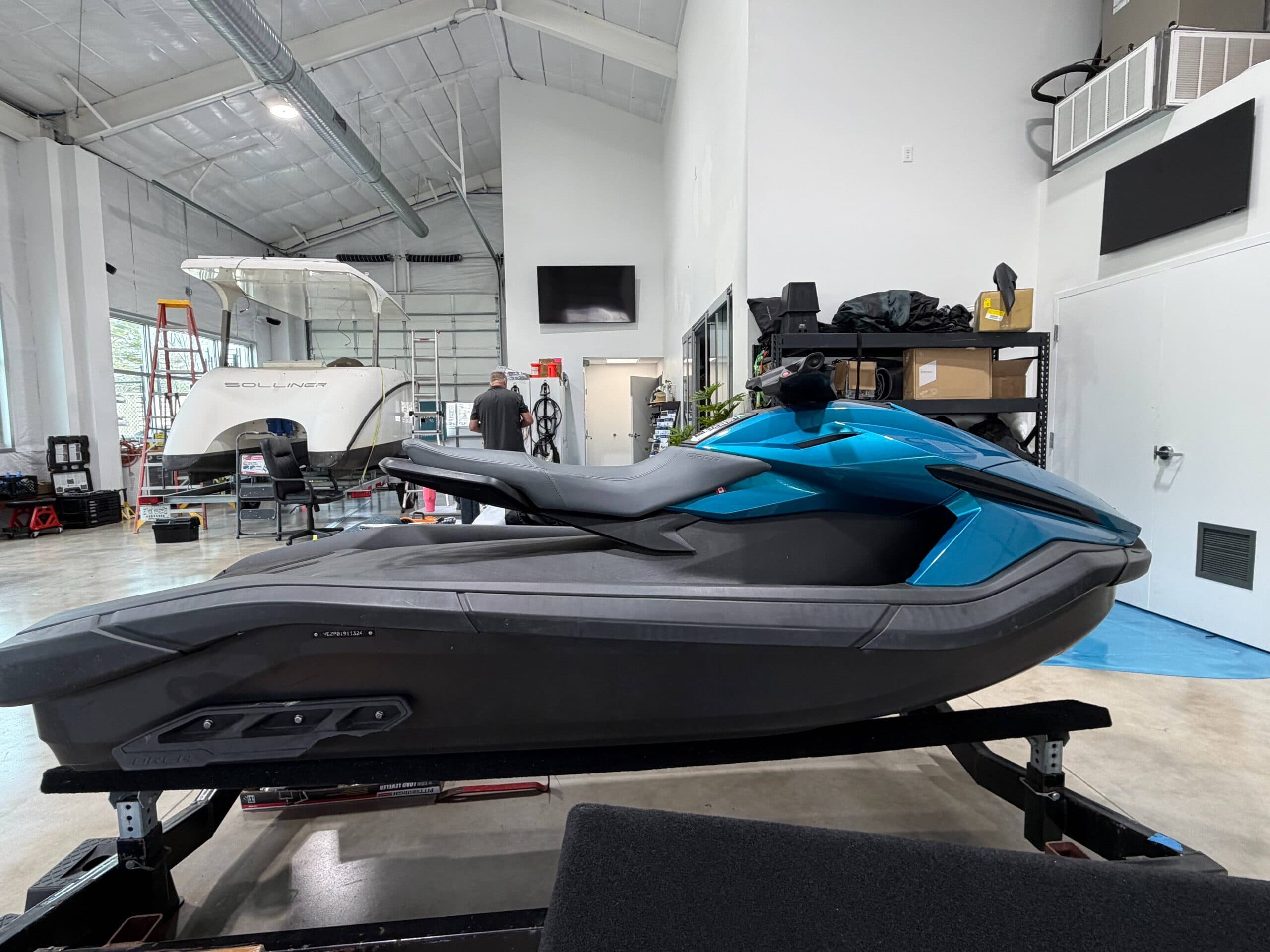 Side view of a blue and black personal watercraft (Taiga Orca P2) on a trailer inside a workshop.