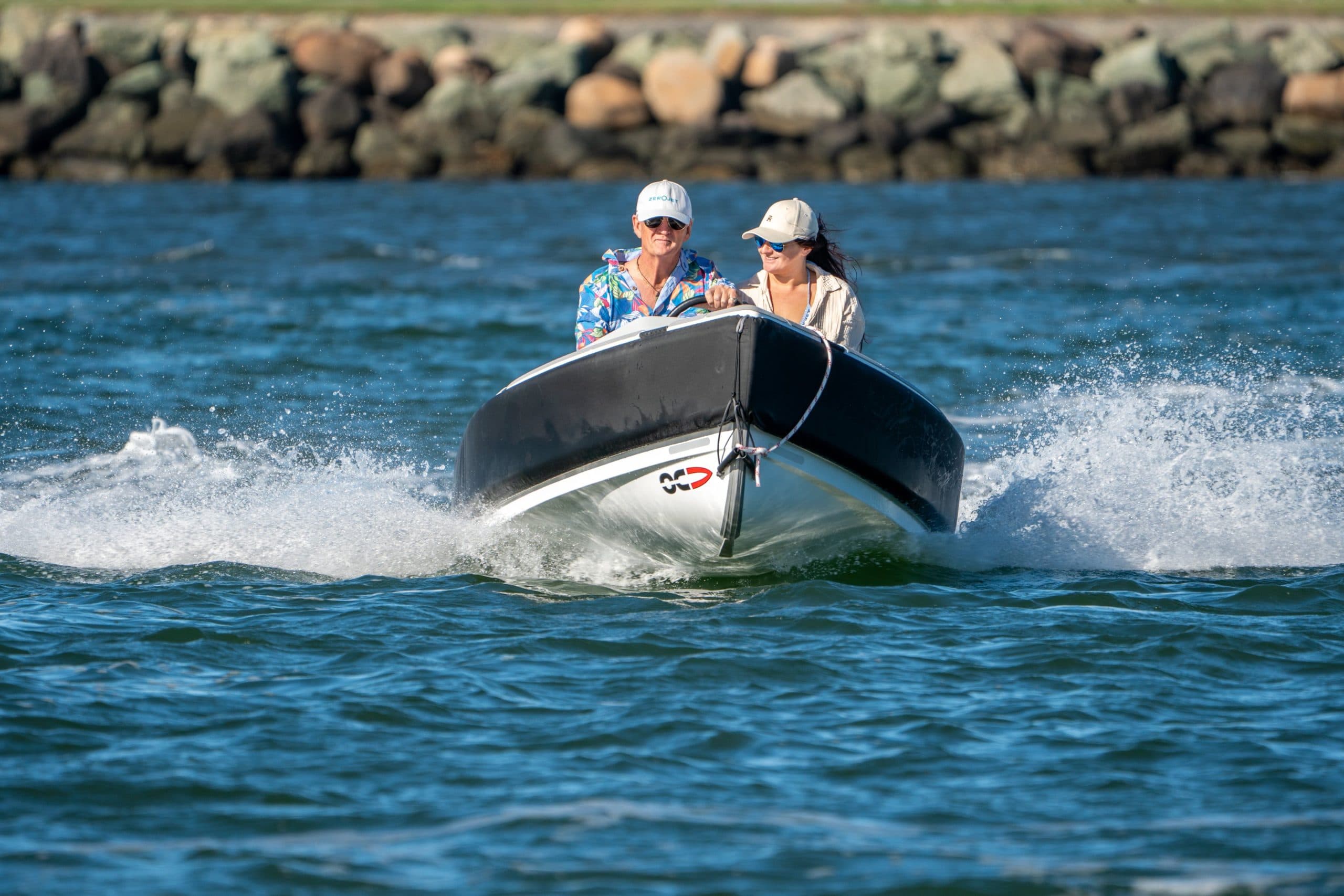 Front view of an Offshore Cruising Tenders OC350 tender underway, with two people behind the bow and water splashing around the hull.