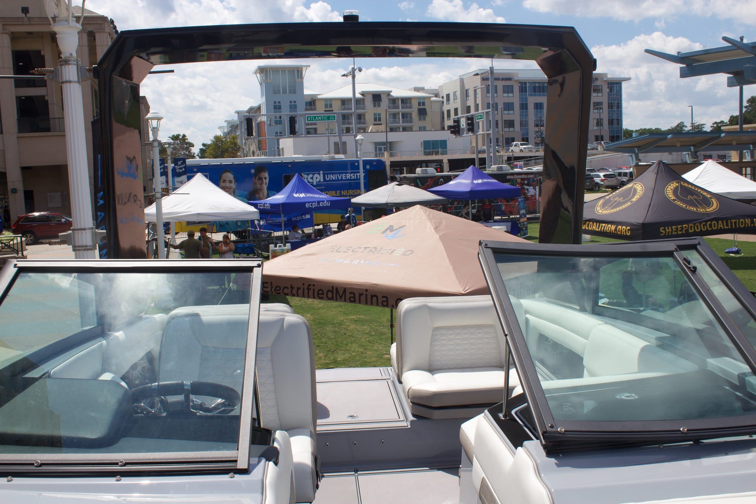 View from the bow into the cockpit of a white recreational boat, showing split windshields, seating, and a wakeboard arch.