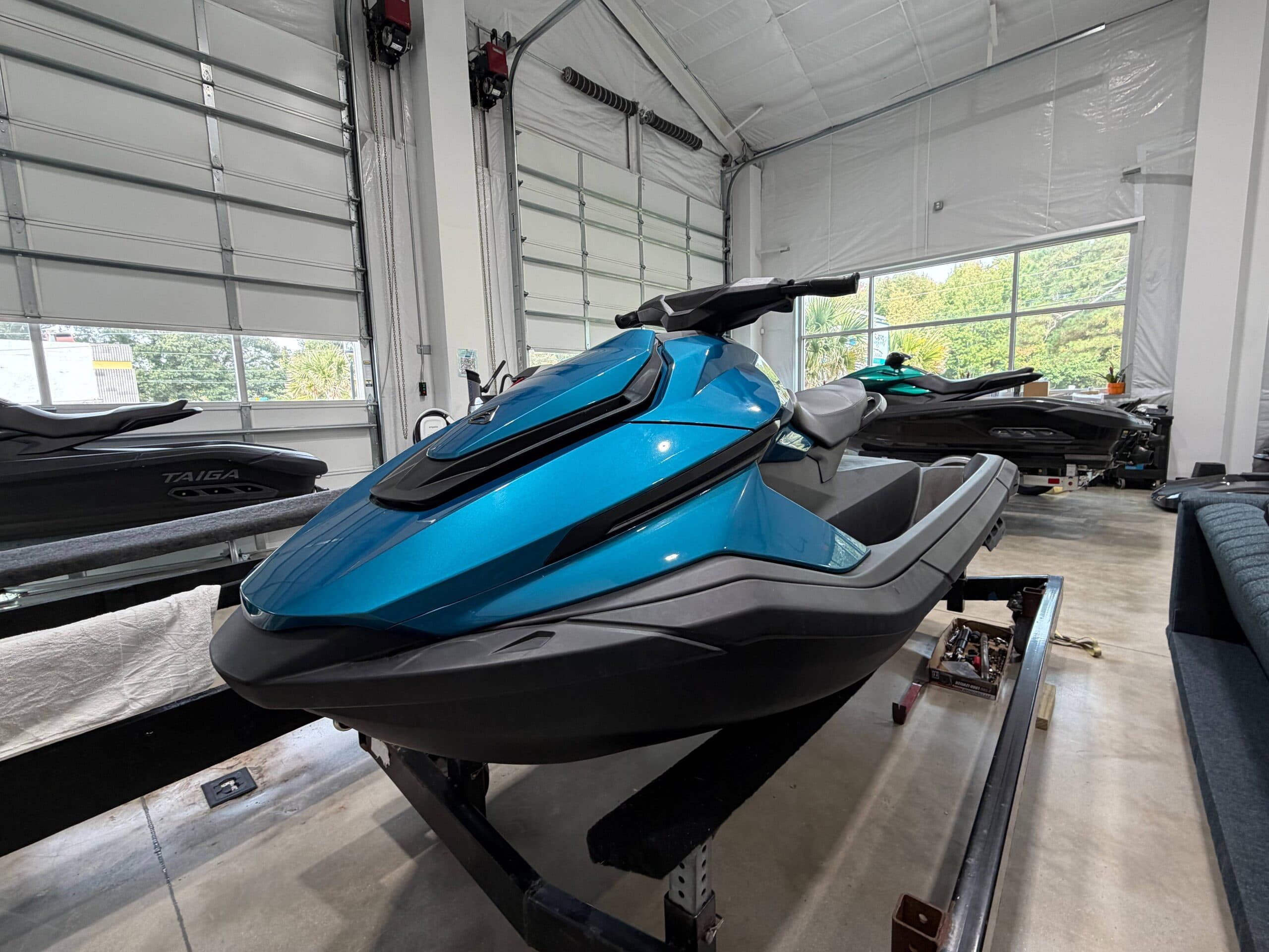 Blue Taiga Orca P2 personal watercraft viewed from the front-left, displayed on a trailer indoors.