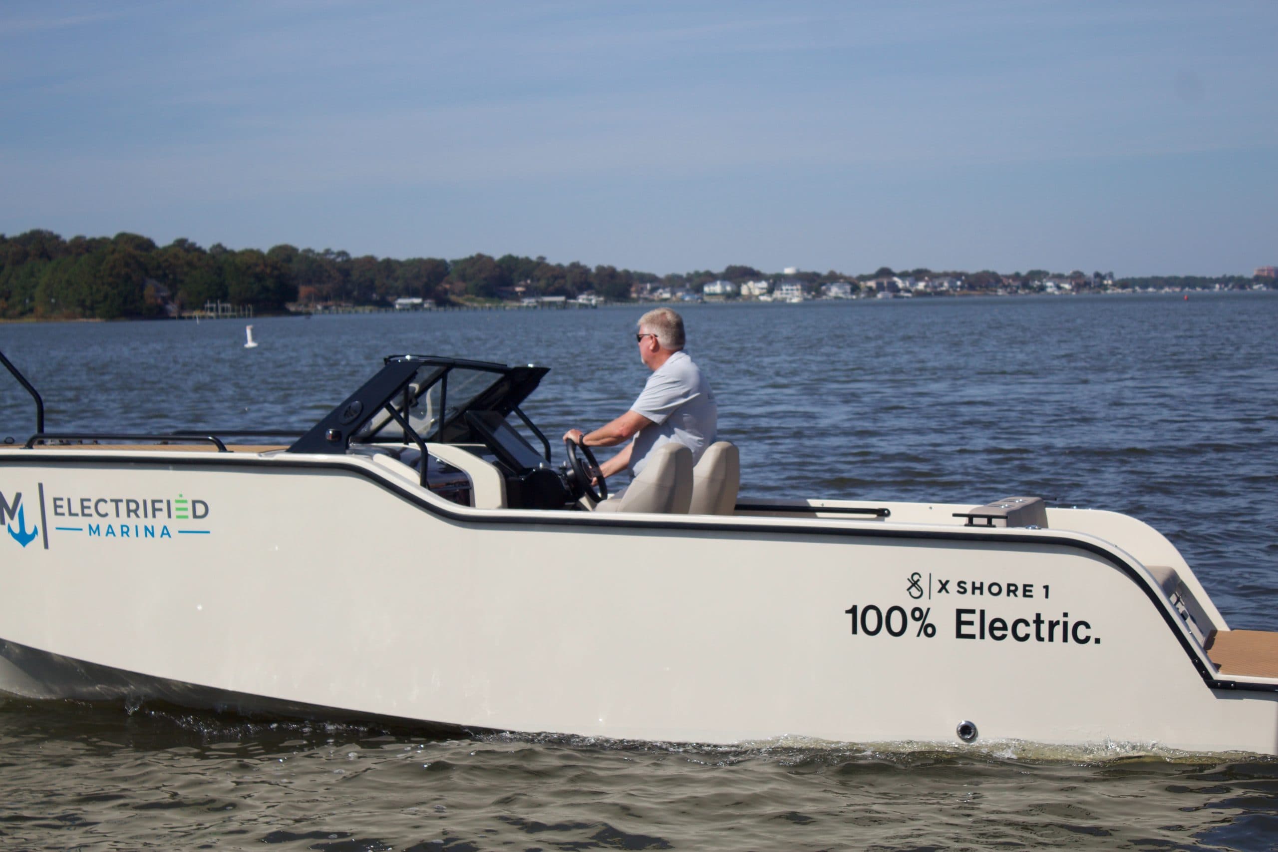 Side view of the X Shore XS1 underway, showing the helm and aft cockpit with a seated person.