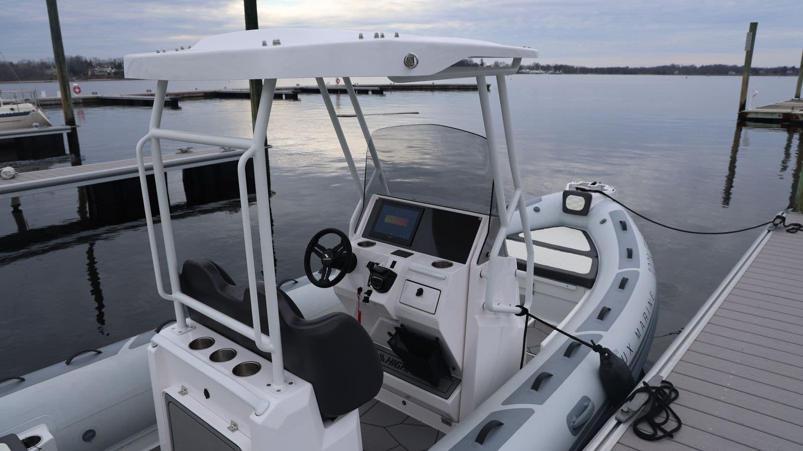 Highfield Sport 660 center-console boat with white T-top docked on calm water.