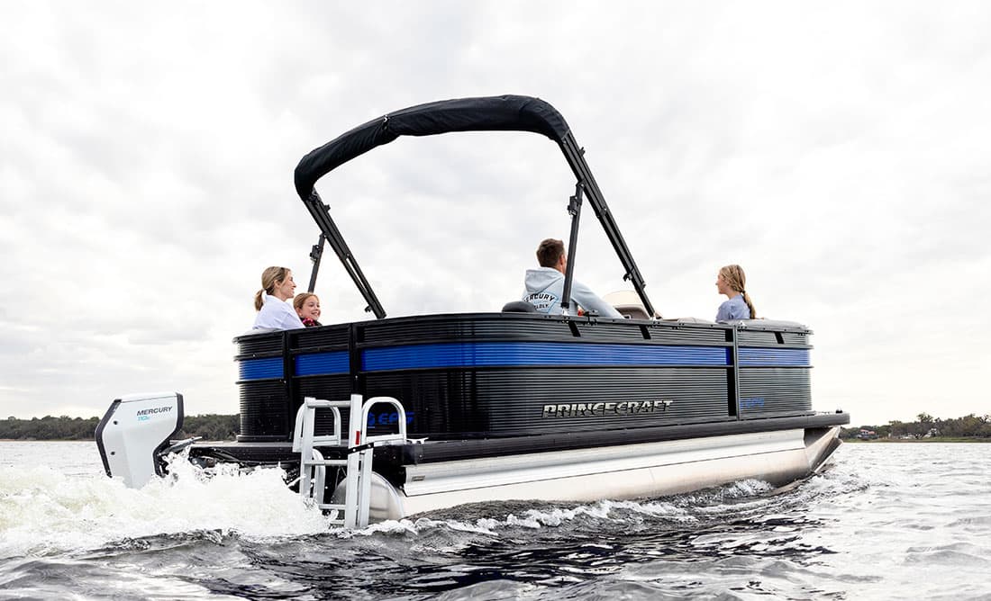 2026 Princecraft Brio e 17 underway, viewed from the rear starboard side, with an outboard motor and passengers aboard.