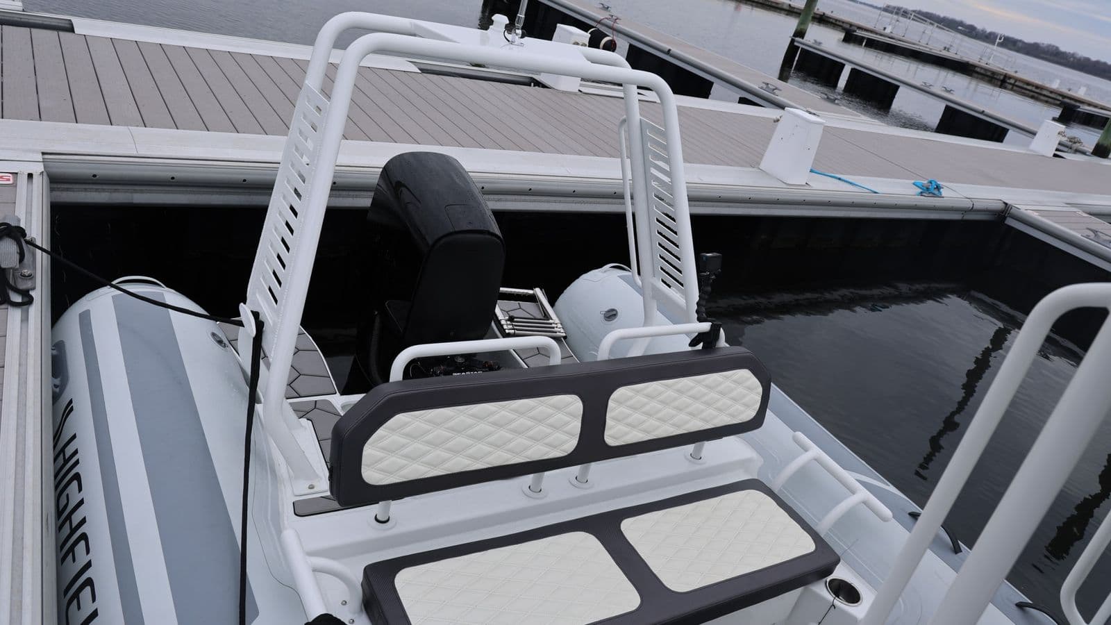 Rear seating and railings of a Highfield Sport 660 inflatable boat moored beside a dock.