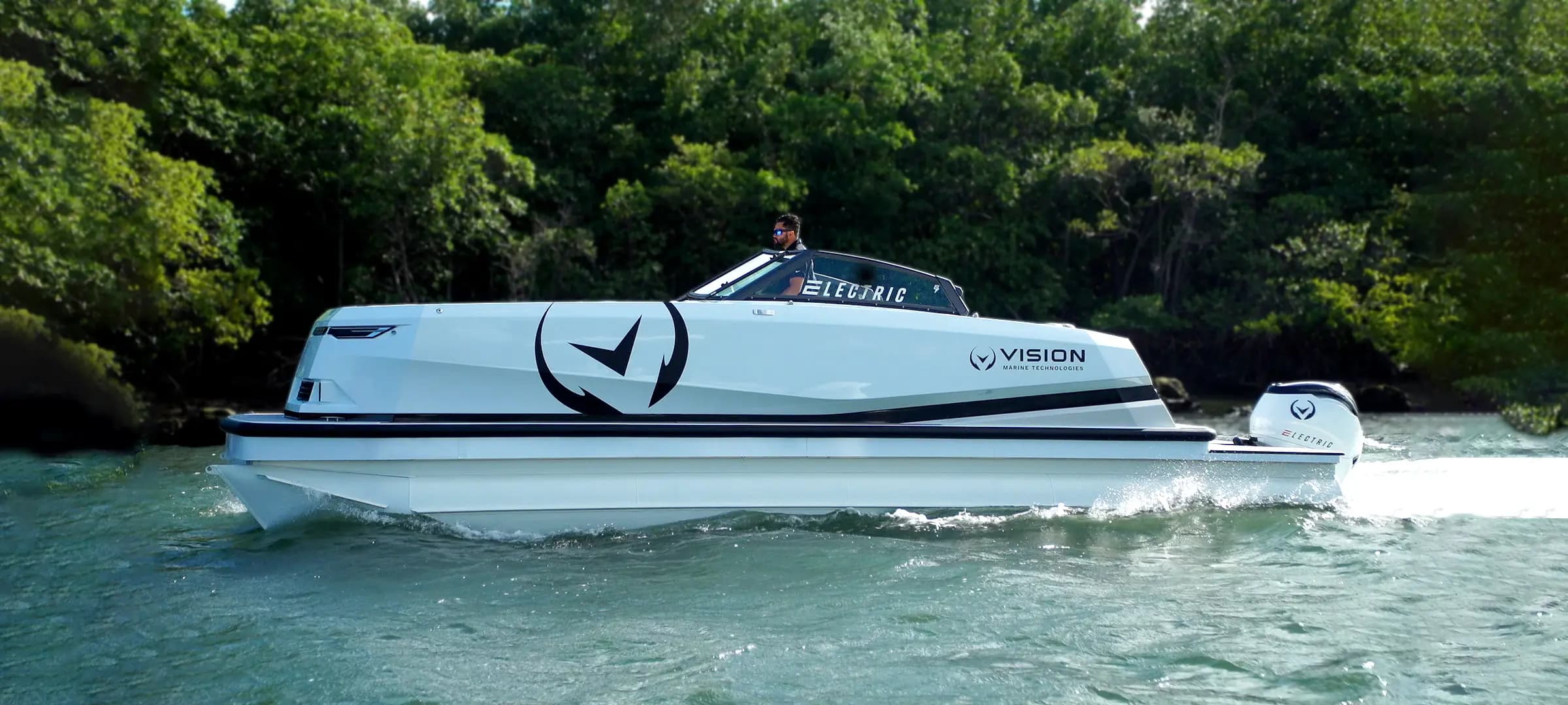 Vision Marine logo on side of white boat cruising on a tree-lined waterway with one captain on board