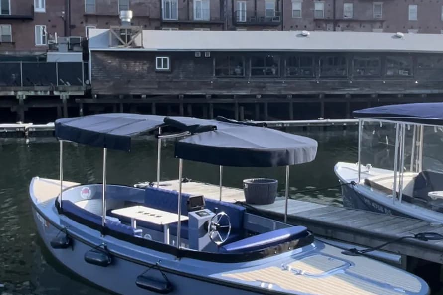 Vision Marine Fantail 217 Blue electric-style pontoon boat with canopy, seating, helm, and swim platform docked on a waterfront.